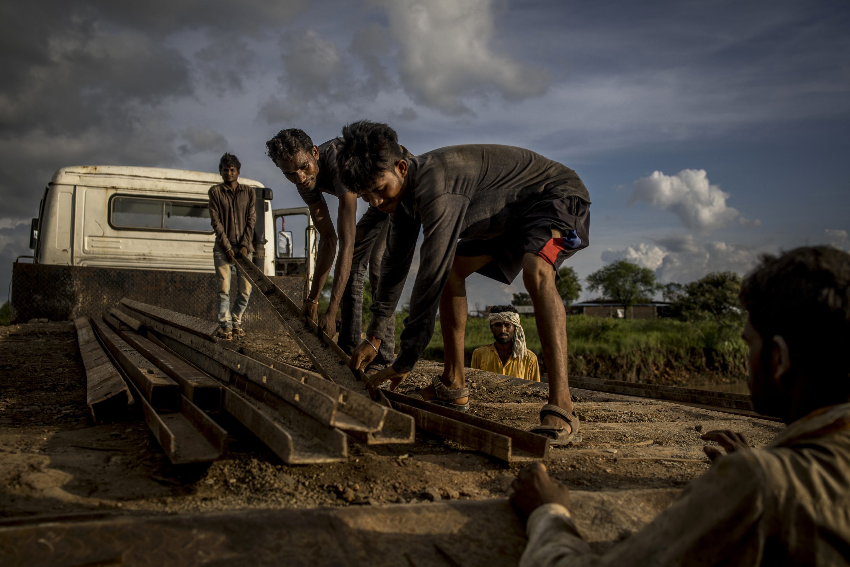 Workers unload construction materials from a truck at the site of a flyover in Guna, Madhya Pradesh, India, on Sunday, Sept. 12 2021.