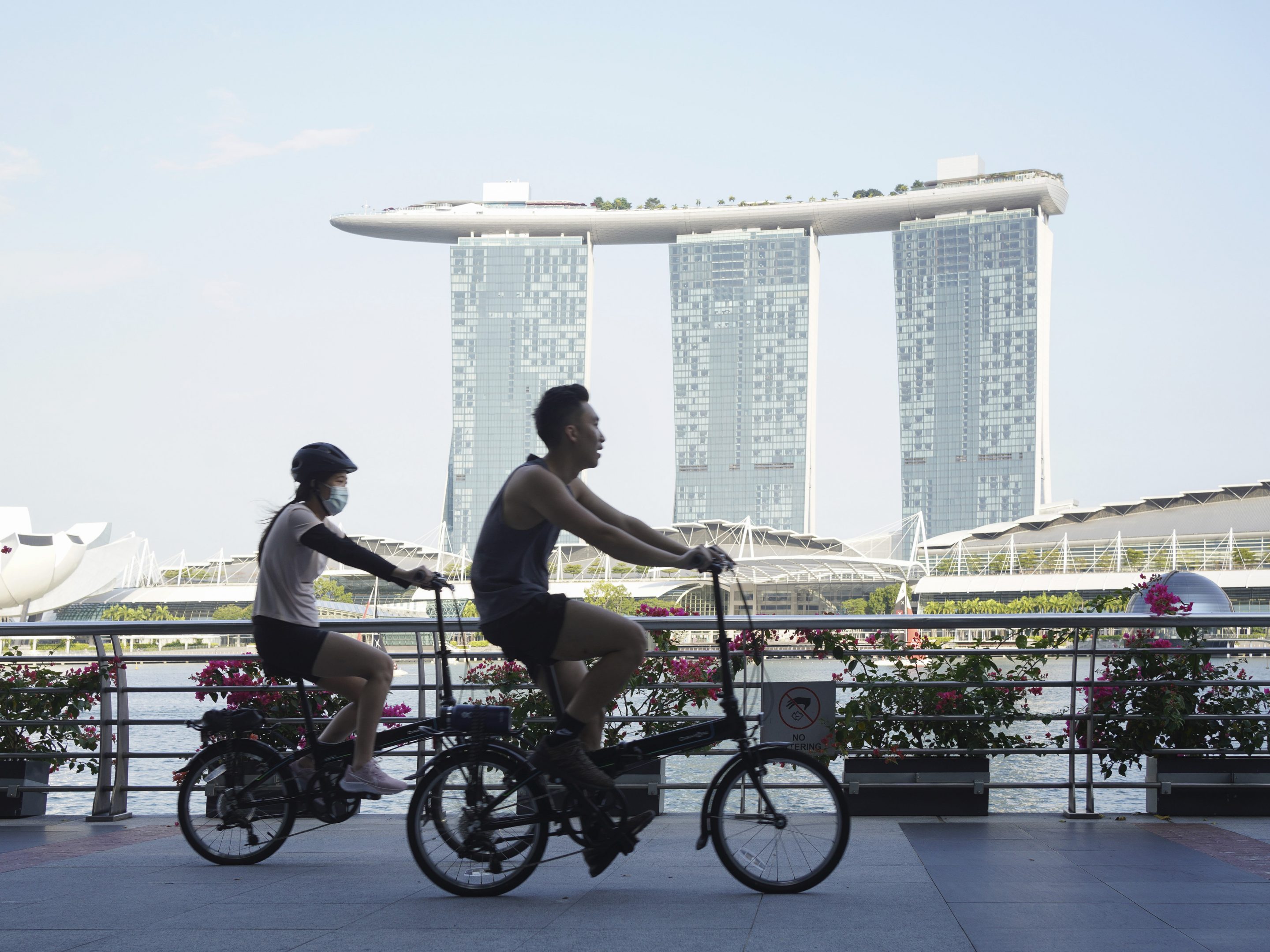 Cyclists ride past the Marina Bay Sands Hotel in the Marina Bay area of Singapore, on Saturday, Sept. 25, 2021.