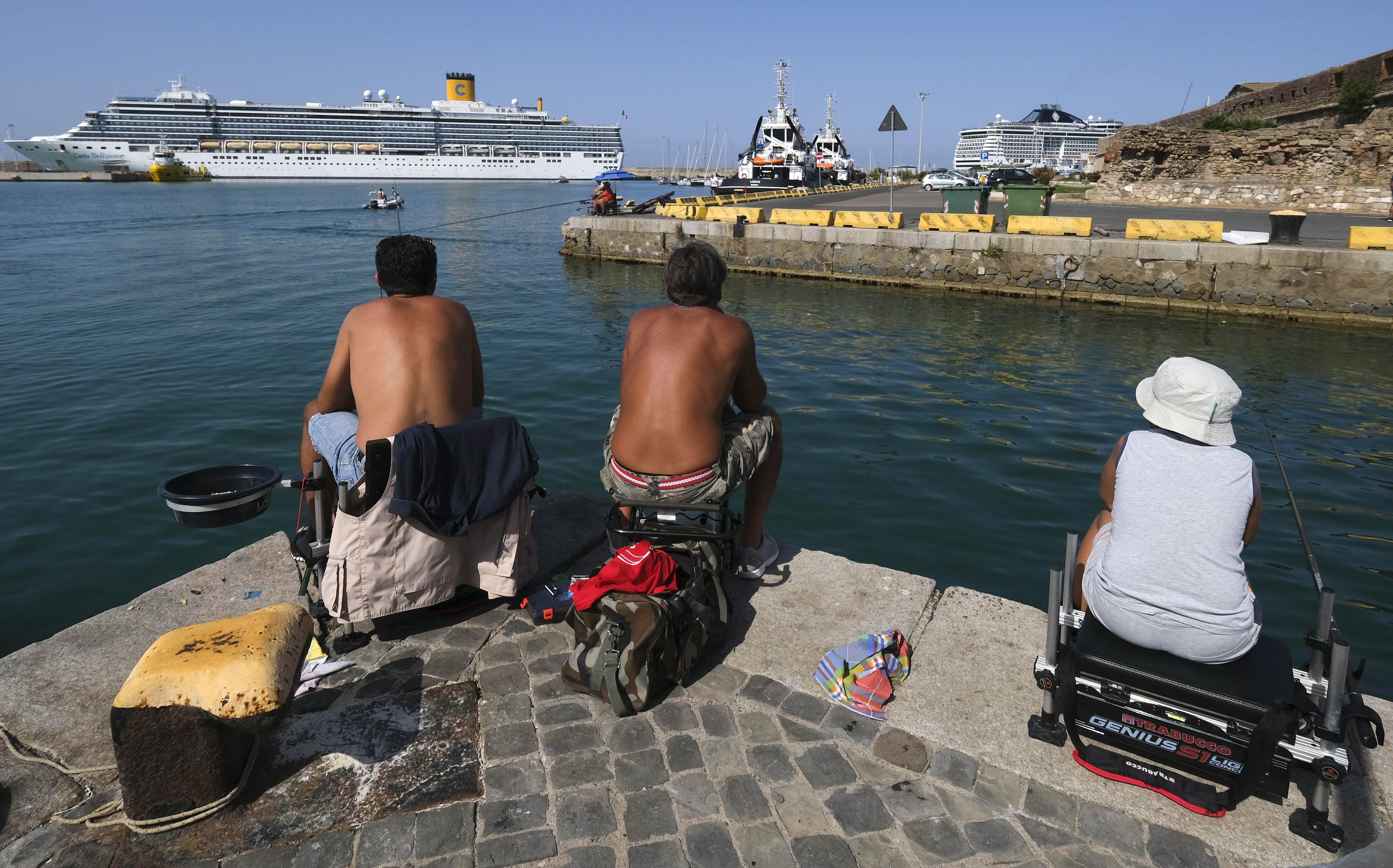 People fishing in front of a Costa Crociere cruise liner docked in the harbor of Civitavecchia, north of Rome. There are cruise ships docked and moored close to ports up and down the country, triggering a campaign between locals and environmentalists to find a new place to park them.
