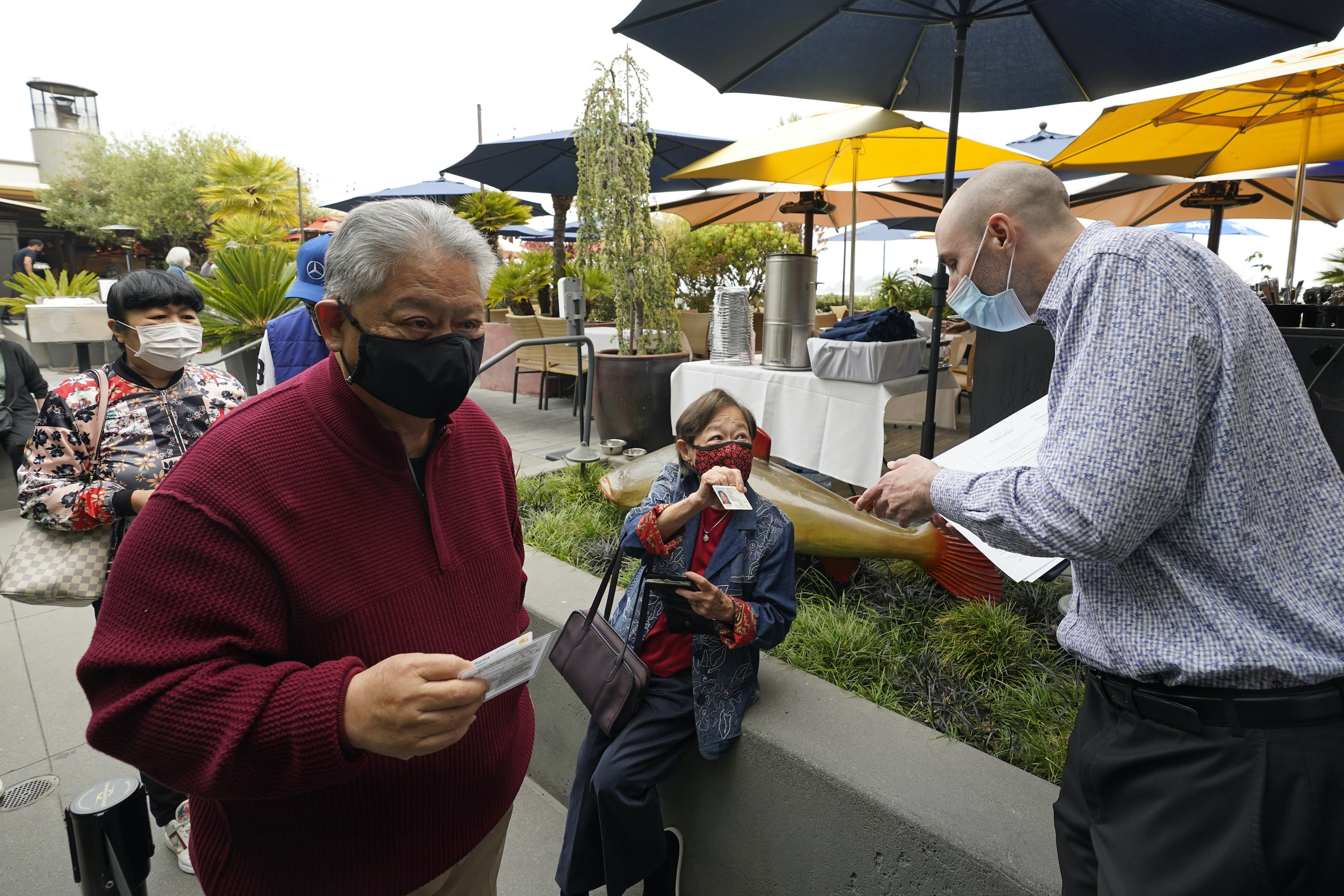 Jason Pryor, right, checks the vaccination and identification cards of diners as they enter the Waterbar restaurant in San Francisco on Aug. 20, 2021.