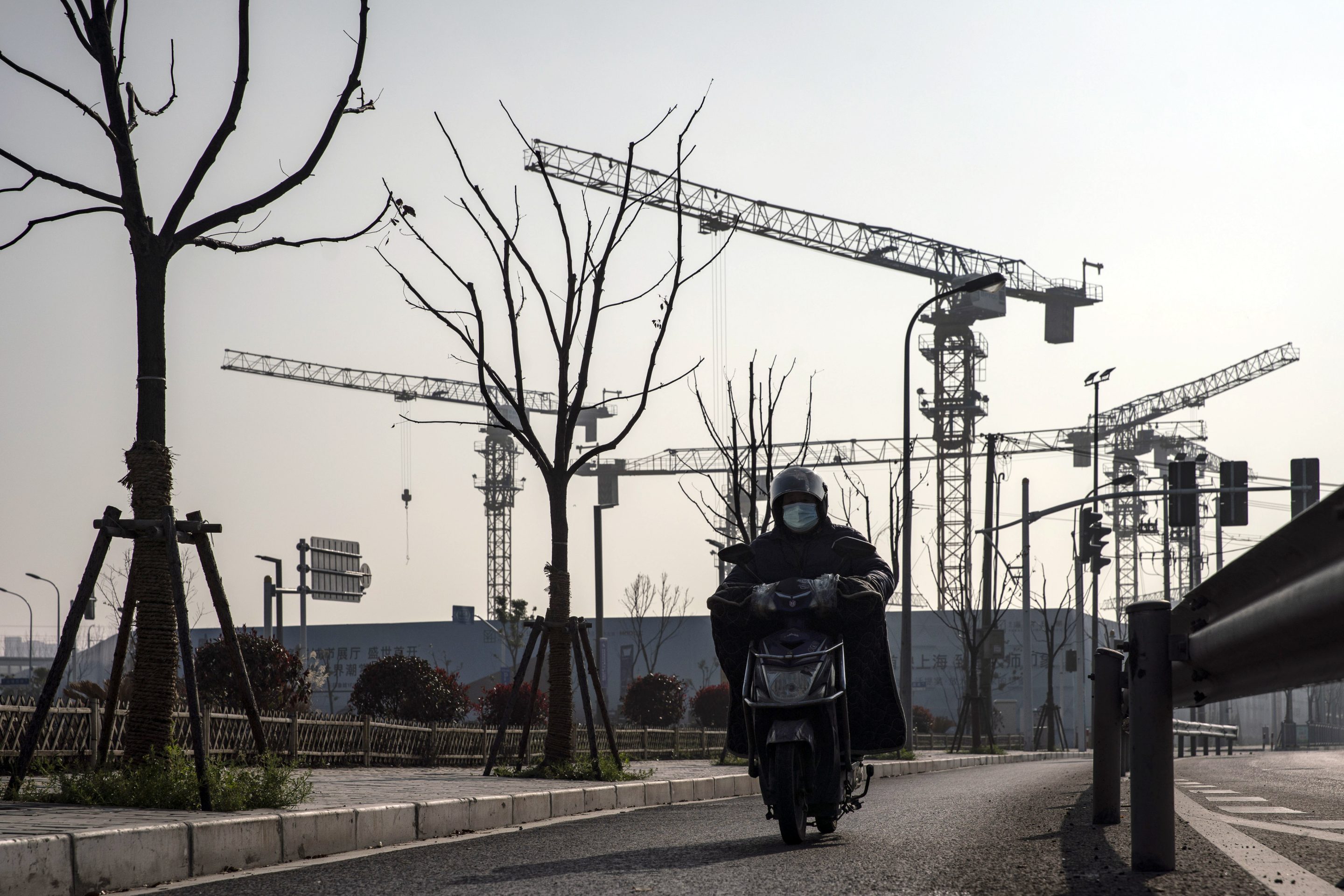 A motorist travels past cranes at a construction site for a residential development on the outskirts of Shanghai, China, on March 14, 2021.