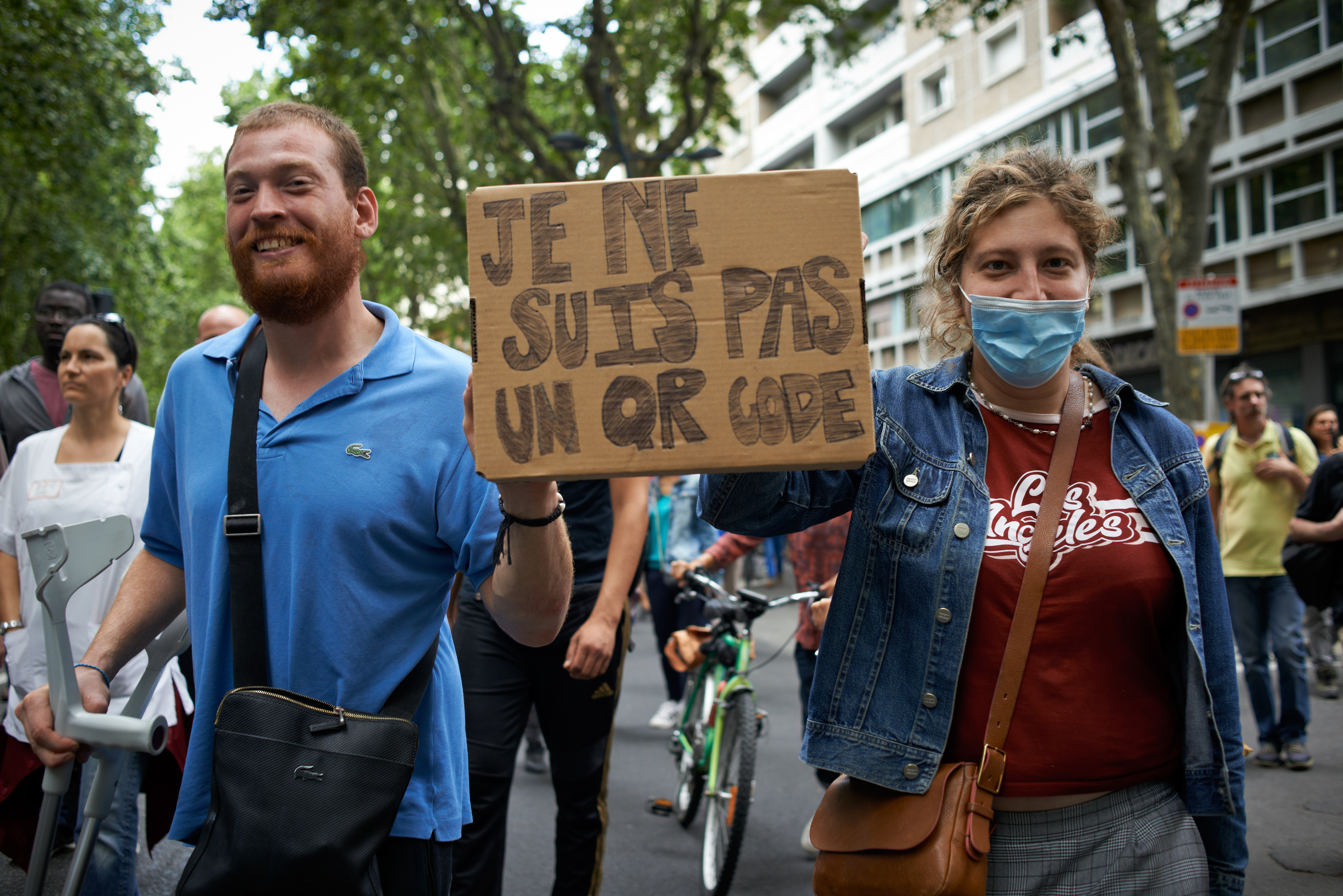 A couple in Toulouse, France, hold a placard reading, “I’m not a QR code.” France and Italy have adopted some of the toughest vaccine mandates in the world for most workers and the general public.