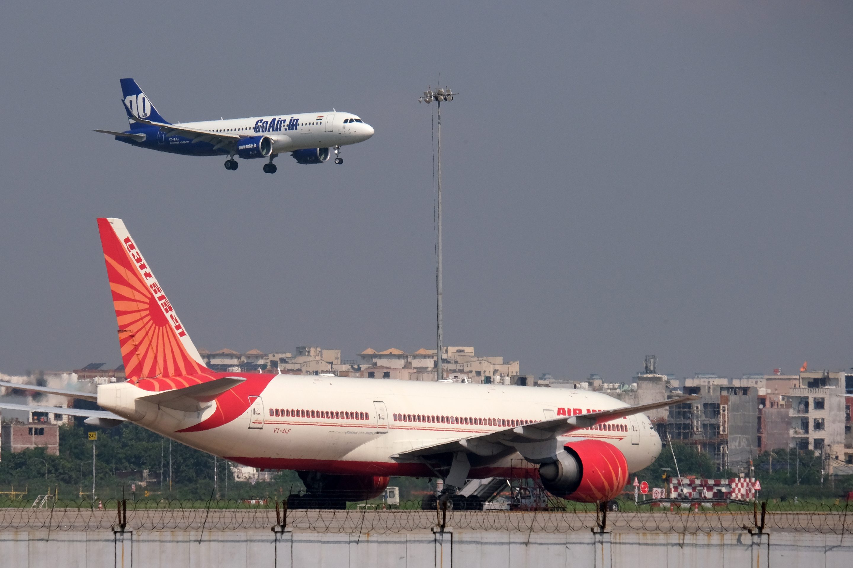 A Go Airlines plane preparing to land flies near an Air India aircraft on the tarmac at the Indira Gandhi International Airport in New Delhi, on Sept. 28 2021.