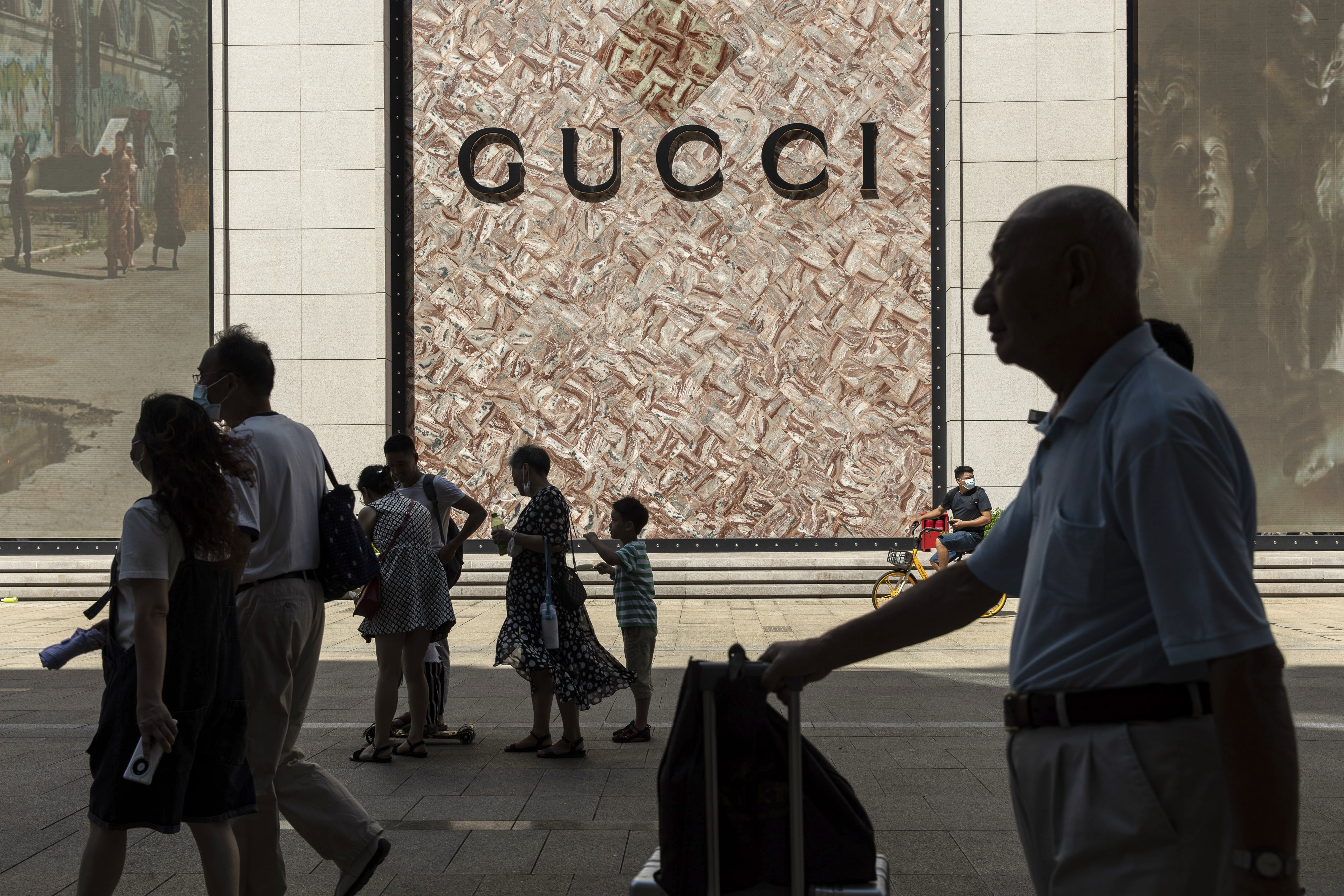 Shoppers and visitors pass a Gucci store while walking along Nanjing Road East in Shanghai, China, on Sunday, Oct. 3, 2021