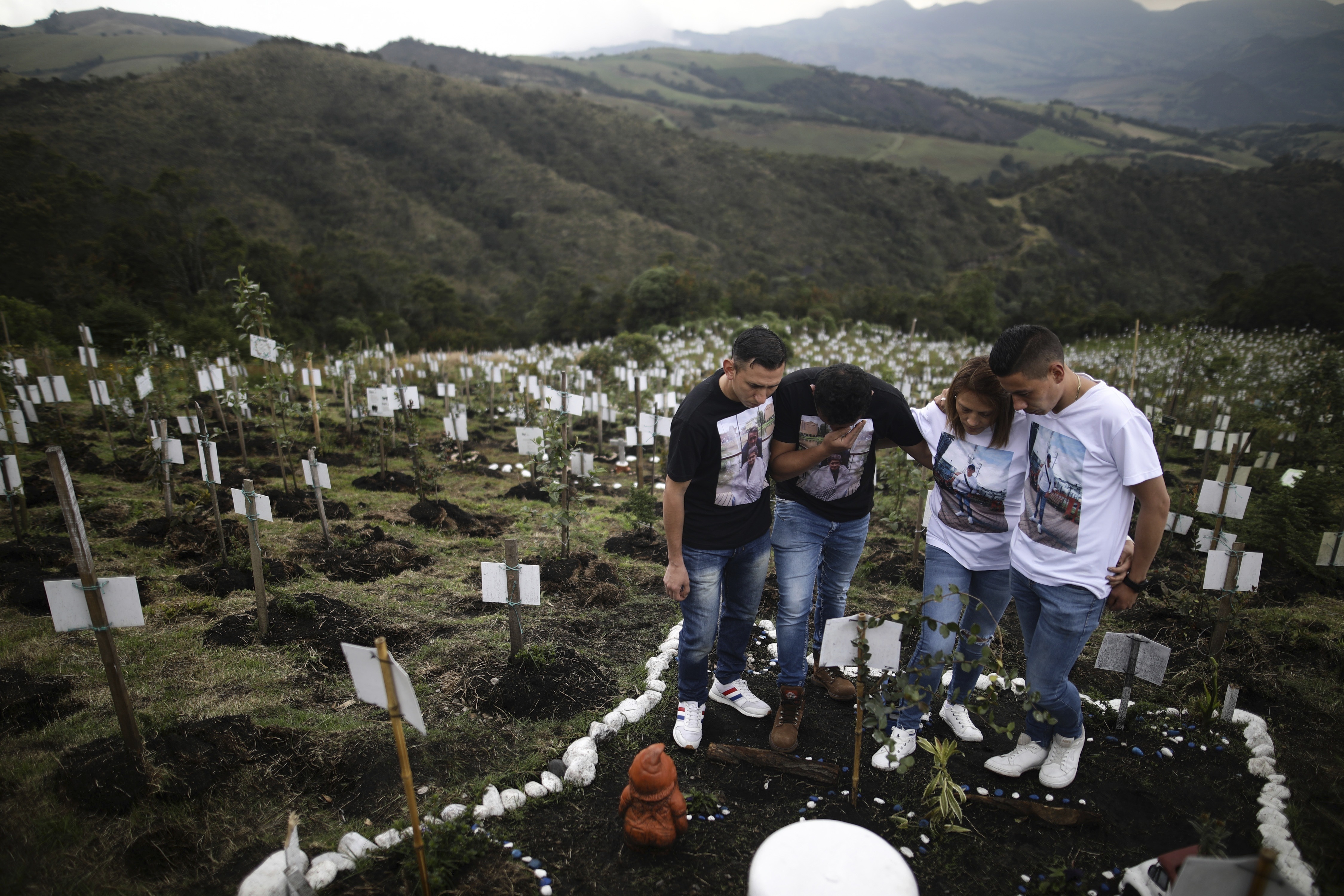 Relatives of Luis Enrique Rodriguez, who died of COVID-19, visit where he was buried on a hill at the El Pajonal de Cogua Natural Reserve, in Cogua, north of Bogota, Colombia, Oct. 25, 2021. Rodriguez died May 14, 2021.