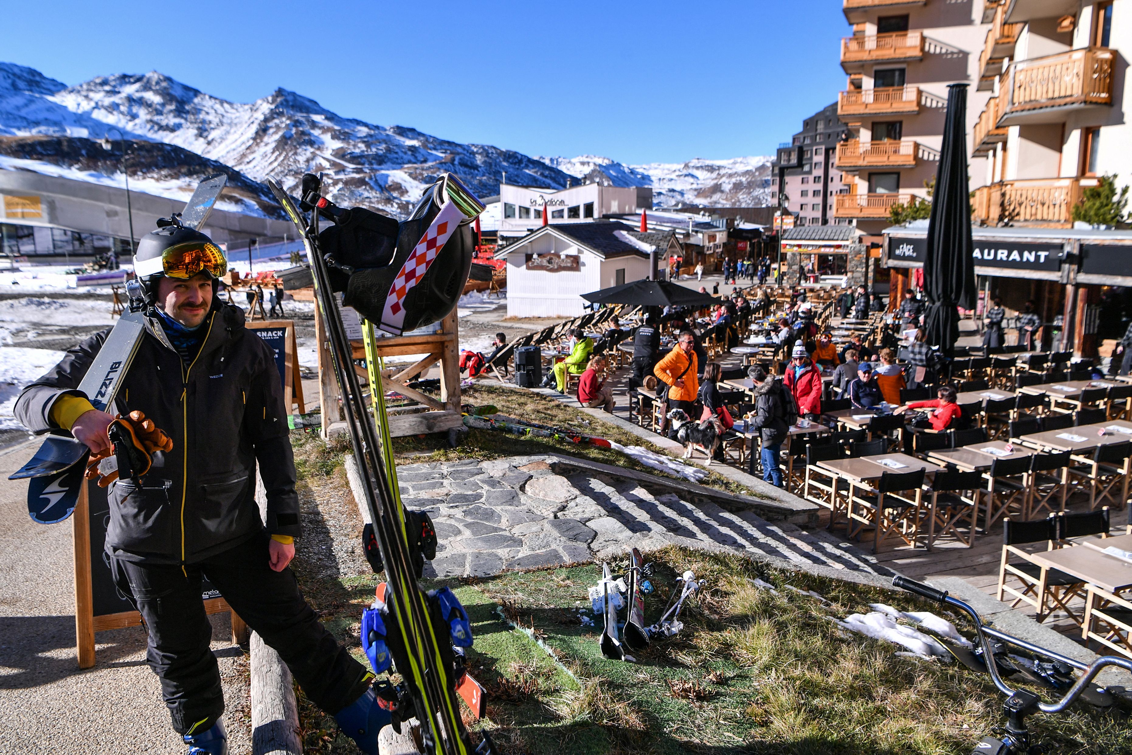 A skier holds his skies next to a restaurant terrace at Val Thorens ski resort, in the French Alps, south-eastern France, during the ski station's opening week-end, on Nov. 20, 2021.