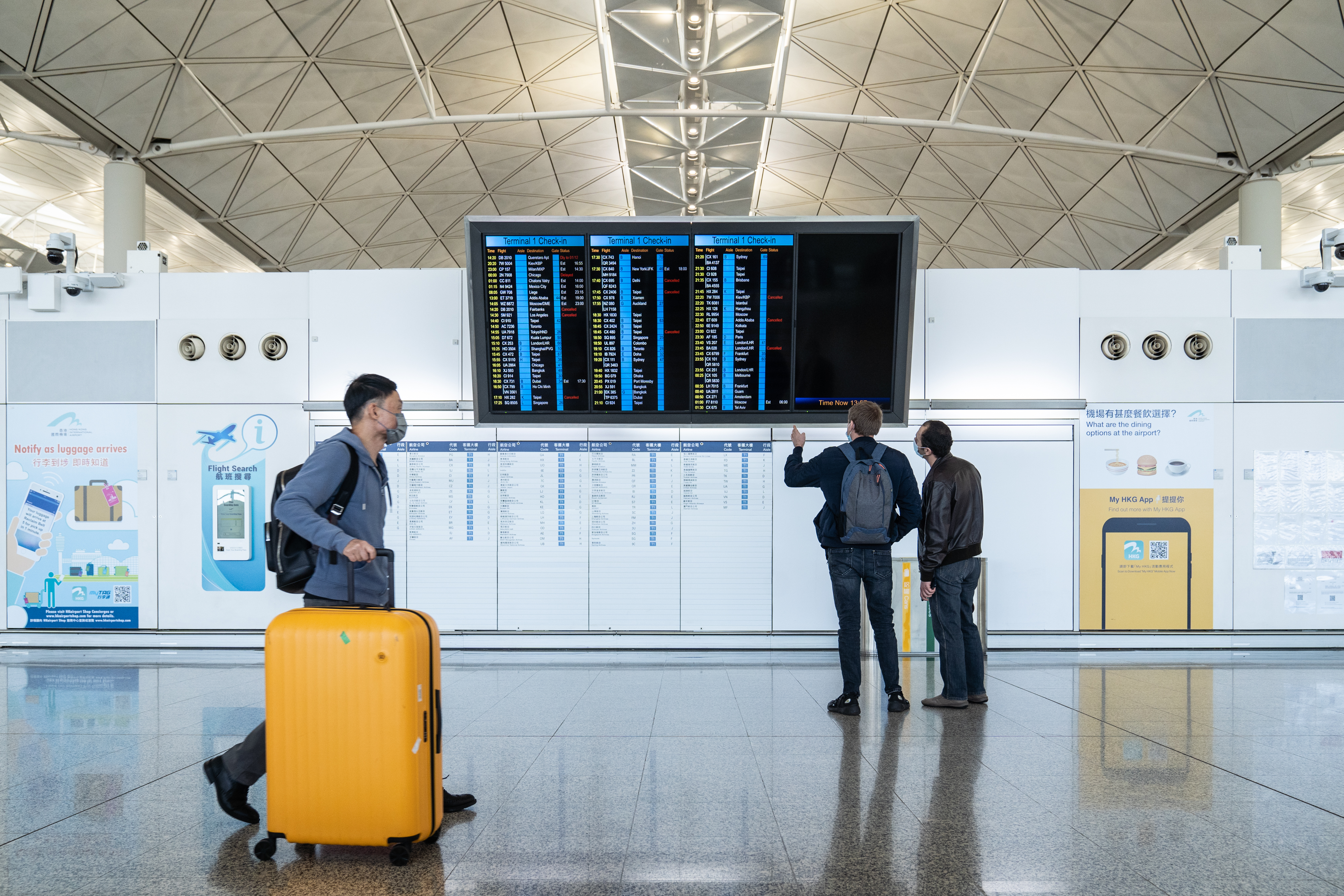 A traveler walks past a flight information panel in the departure hall at Hong Kong International Airport on Nov. 29, 2021.