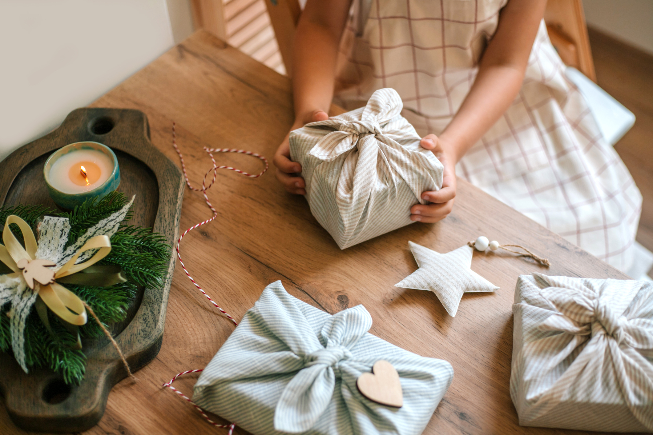 A close-up of a child's hands holding a holiday gift wrapped in Furoshiki-style, a traditional Japanese style that is also being adopted worldwide as a zero-waste concept.