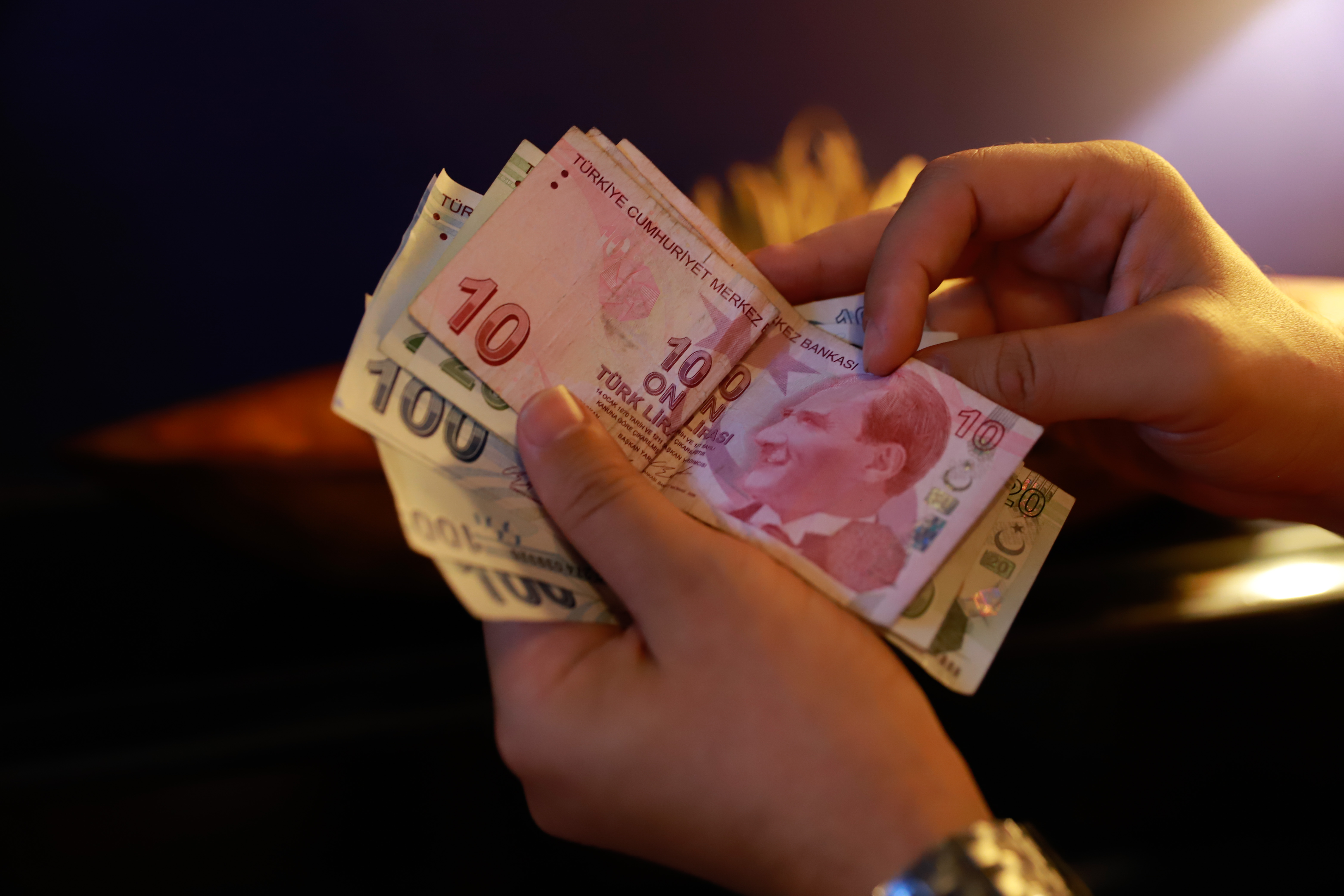 A man holds banknotes of the Turkish lira at a cafe in Izmir, Turkey, on Monday, October 11, 2021.
