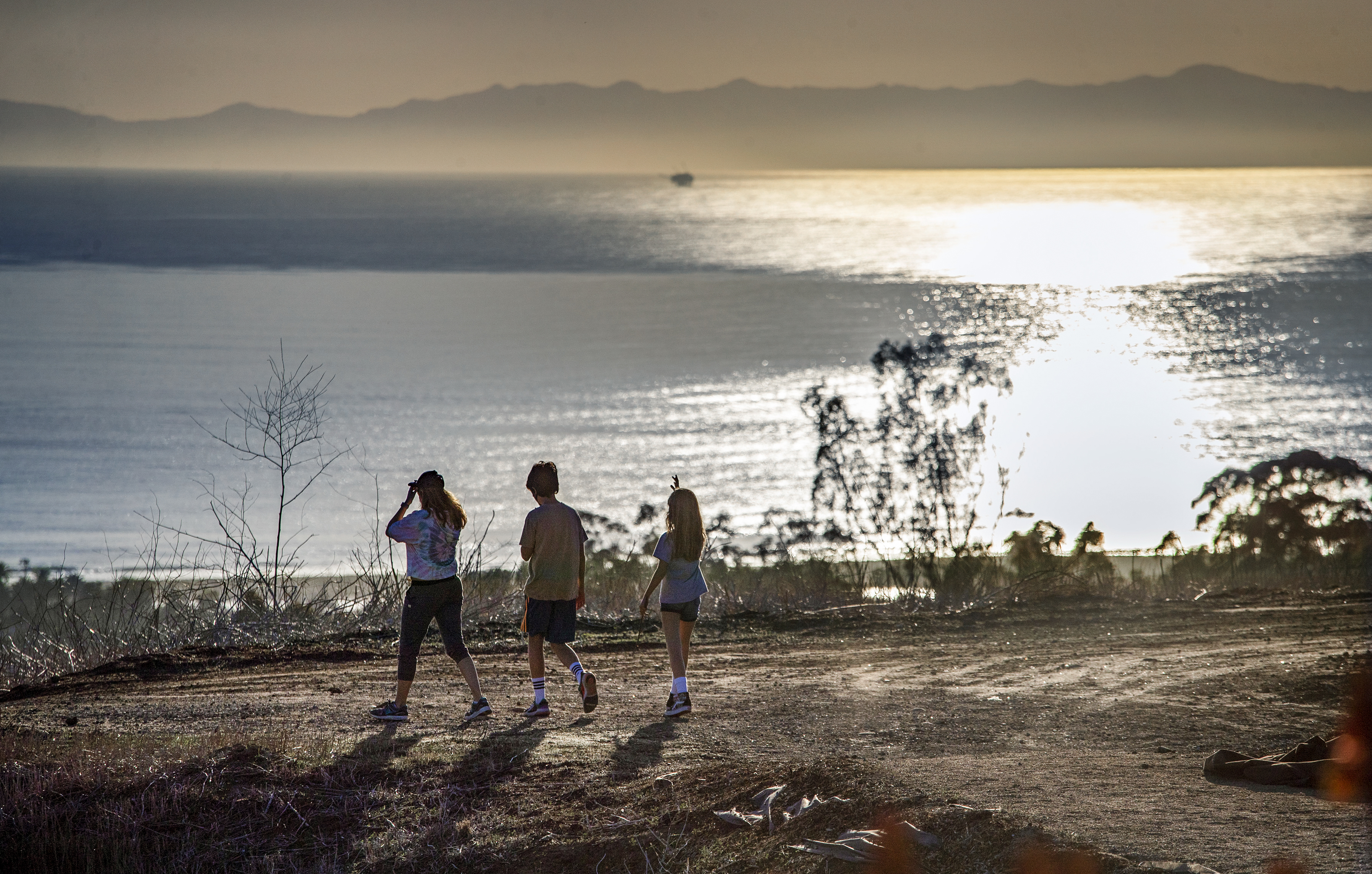 Three hikers enjoy an ocean view in California.
