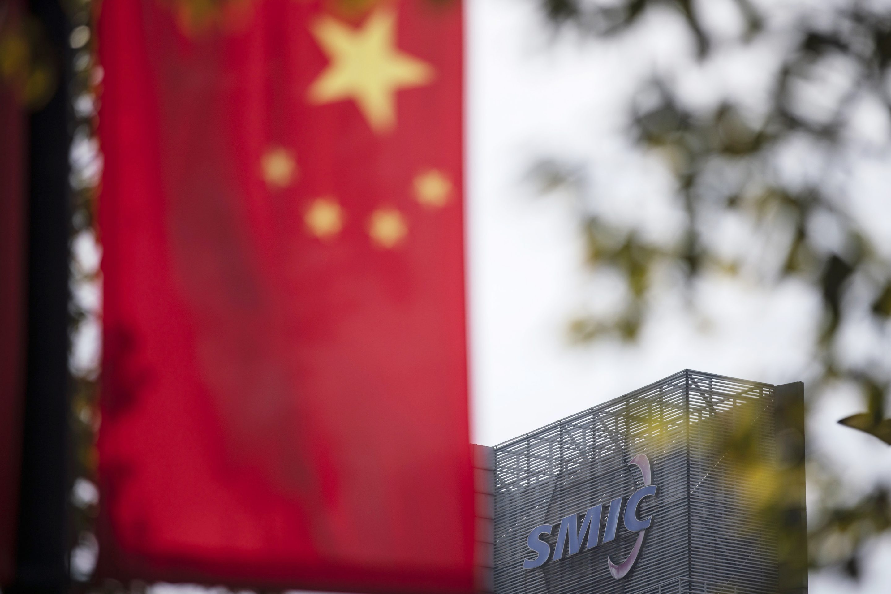 A Chinese flag near a logo atop the Semiconductor Manufacturing International Corp. (SMIC) headquarters in Shanghai, China, on Tuesday, March 23, 2021.