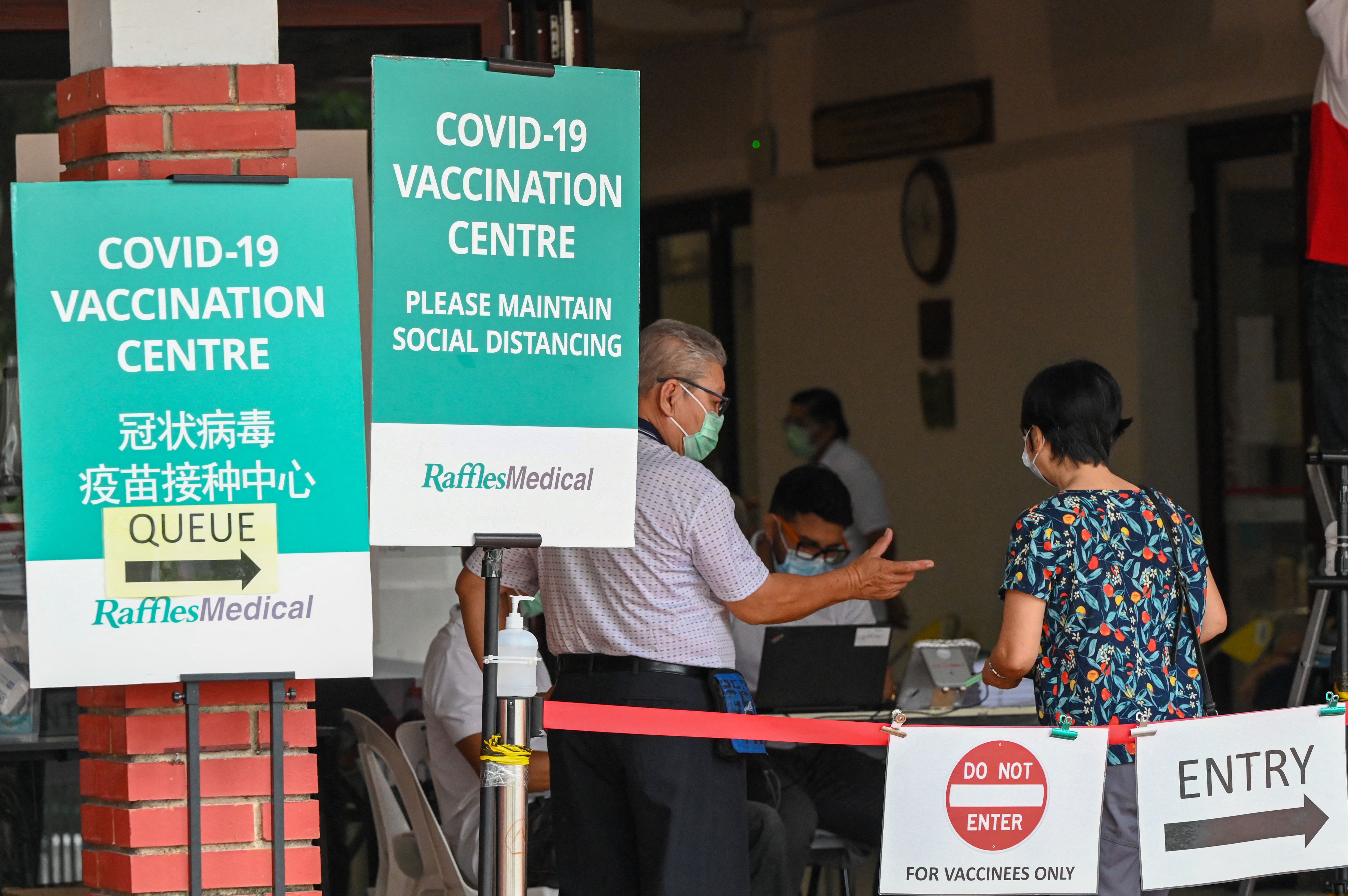 People enter a COVID-19 coronavirus vaccination centre set up at a community centre in Singapore on October 7, 2021. 