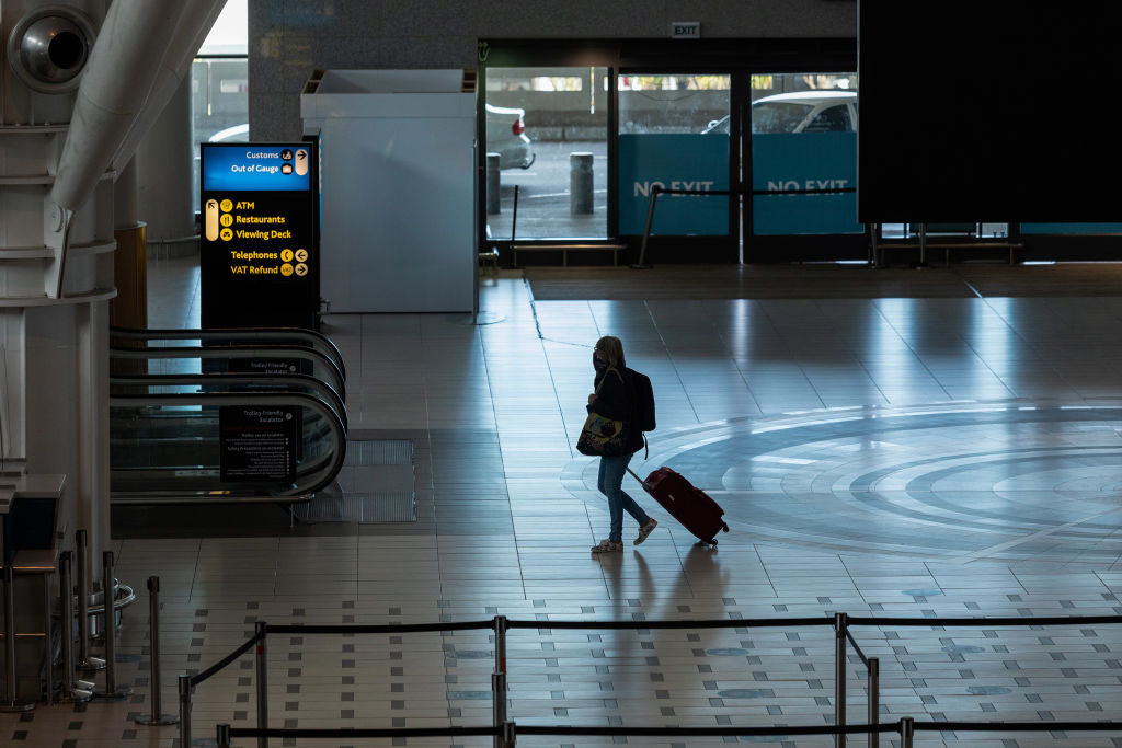 A lone passenger wheels a suitcase through the departures terminal at Cape Town International Airport in Cape Town, South Africa, on Friday, Dec. 3, 2021. South Africa announced the discovery of a new variant, later named omicron, on Nov. 25 as cases began to spike and the strain spread across the globe, with many countries halting flights to and from southern Africa.