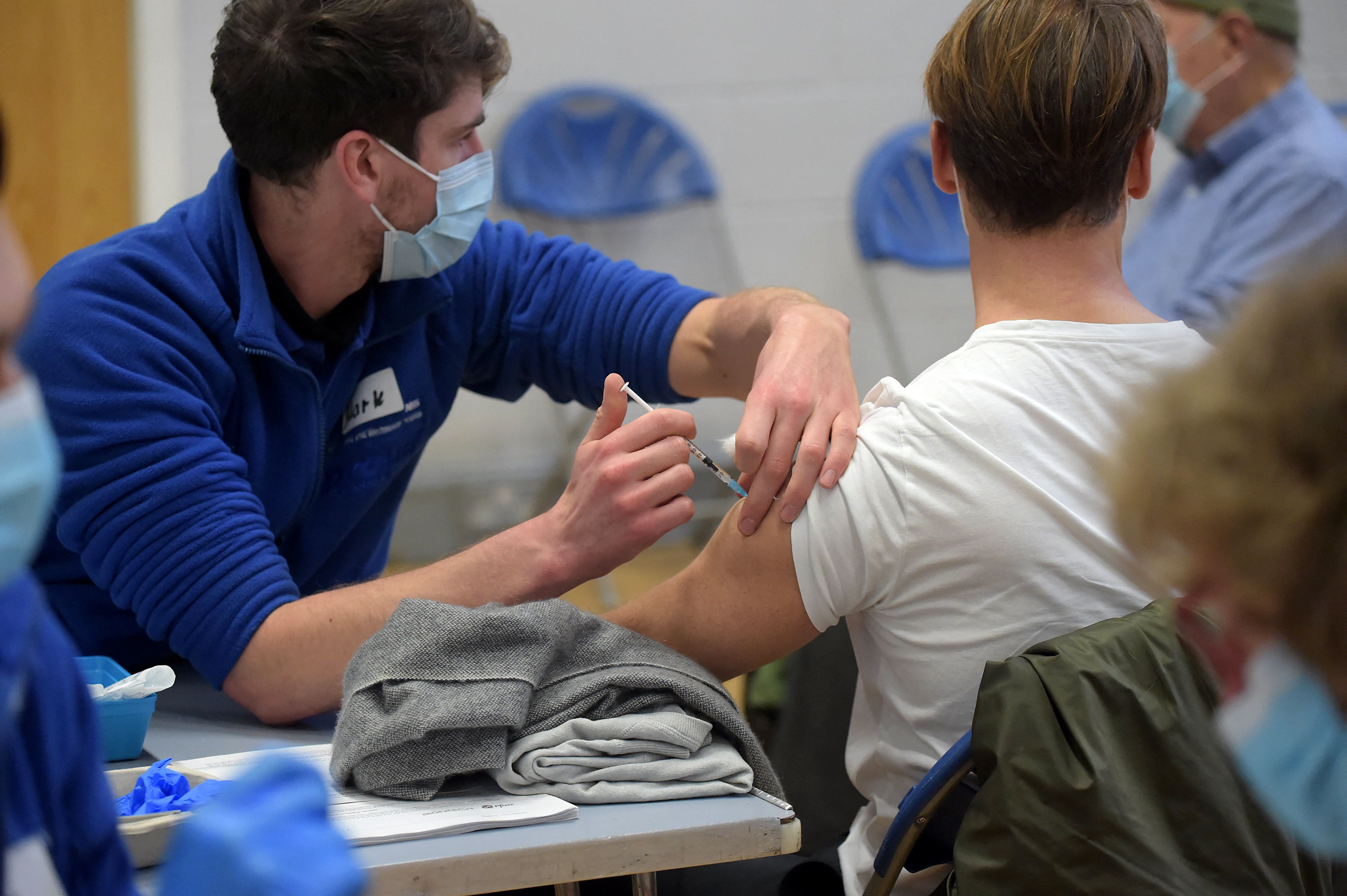 People get vaccinated against COVID-19 during a visit by the British prime minister at the Stowe vaccination centre in central London on Dec. 13, 2021.