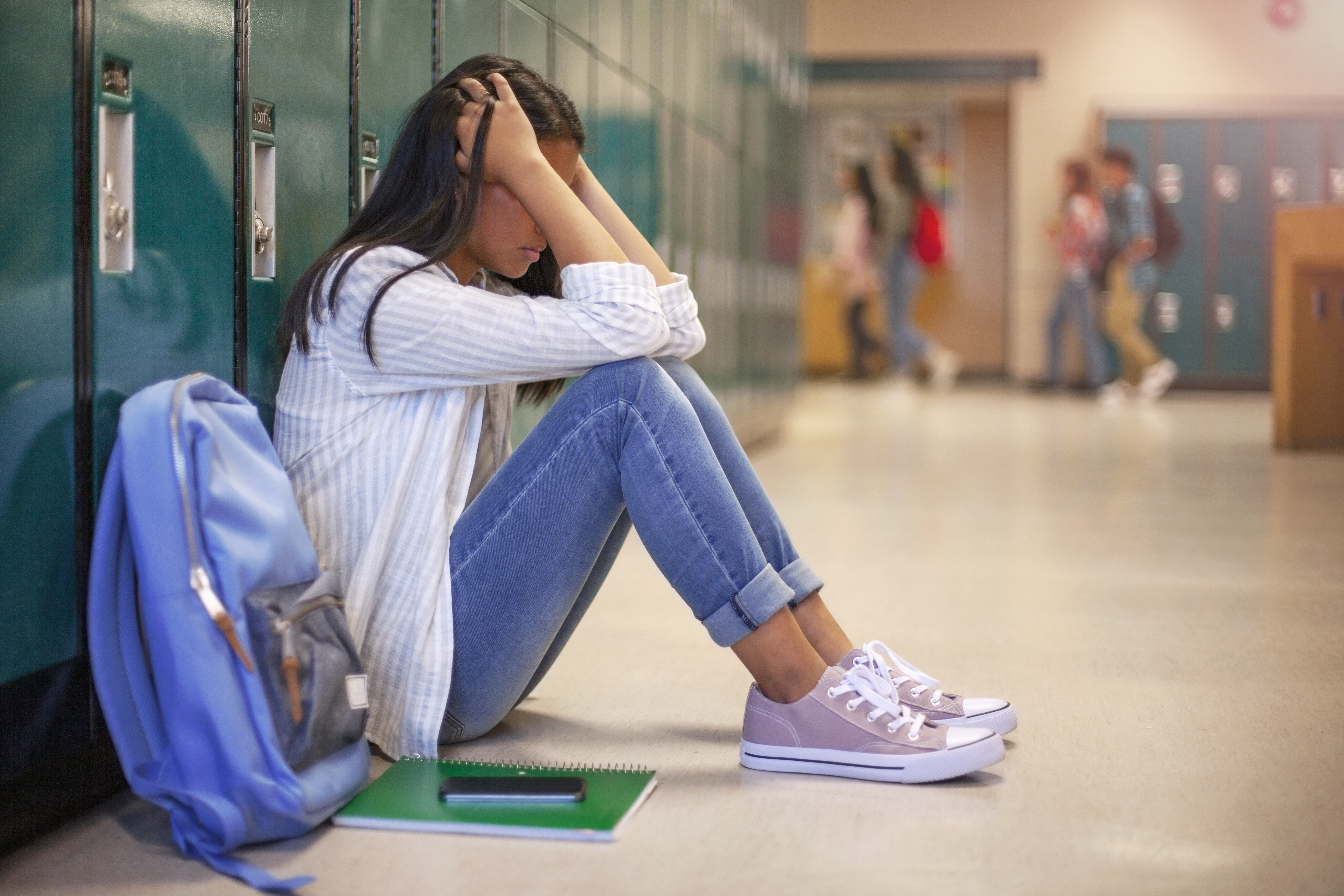 Female student sitting in a school hallway.