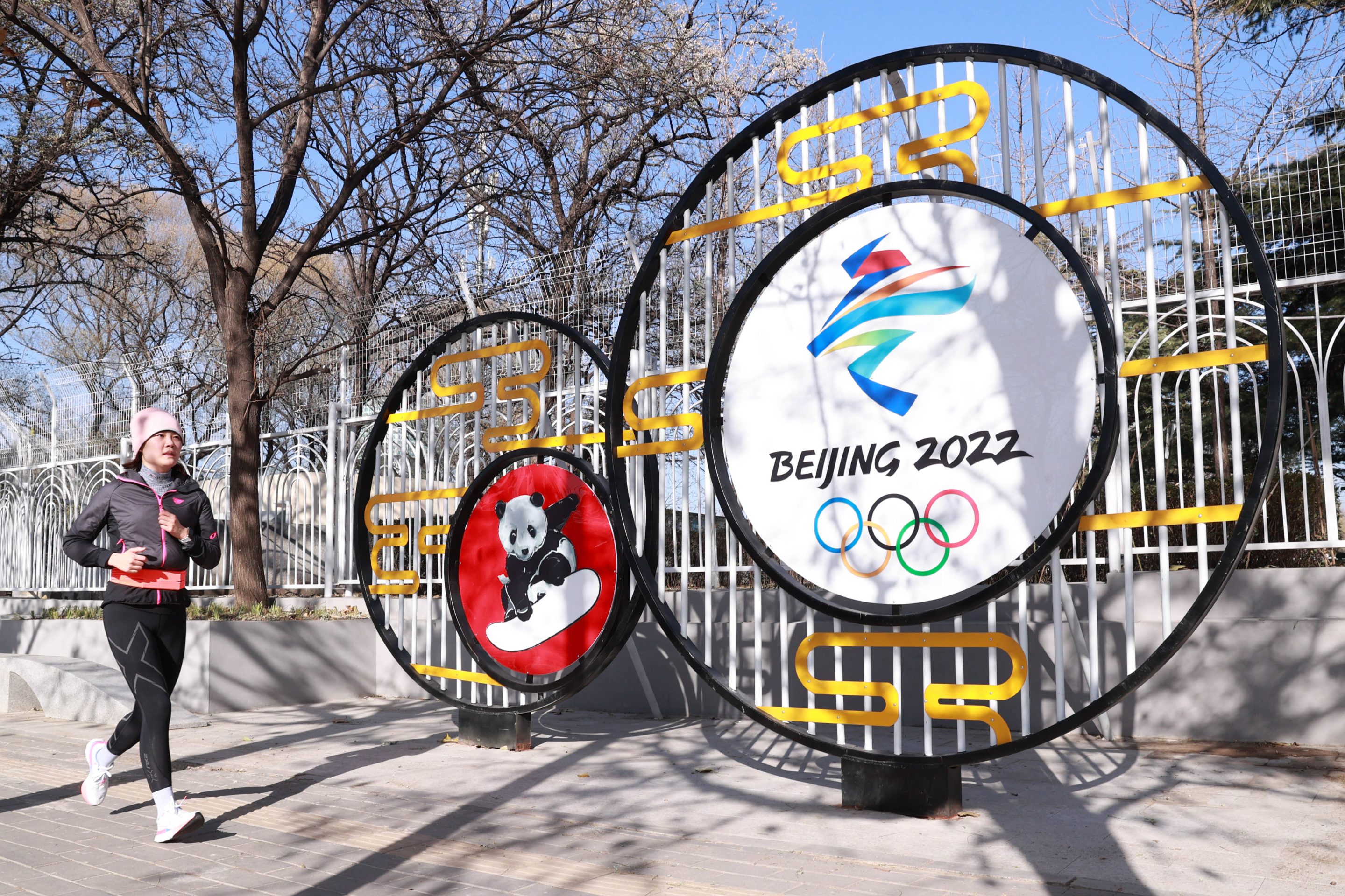 A jogger runs by a street decoration for the Beijing 2022 Winter Olympics at National Olympic Sports Center on November 24, 2021 in Beijing, China.