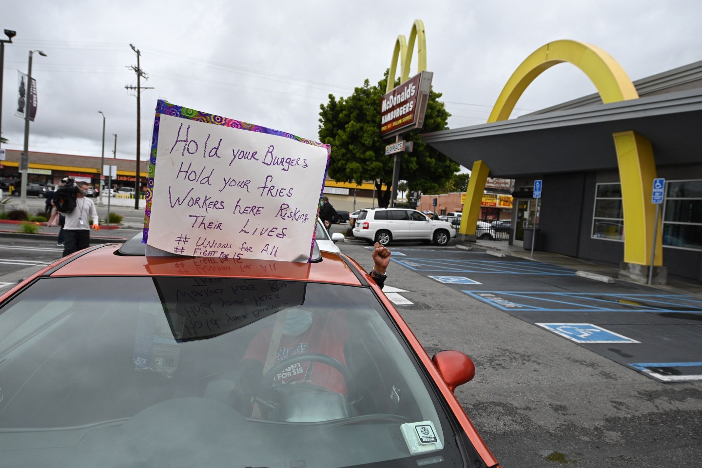 a person in a car holding their fist in the air outside a McDonald's