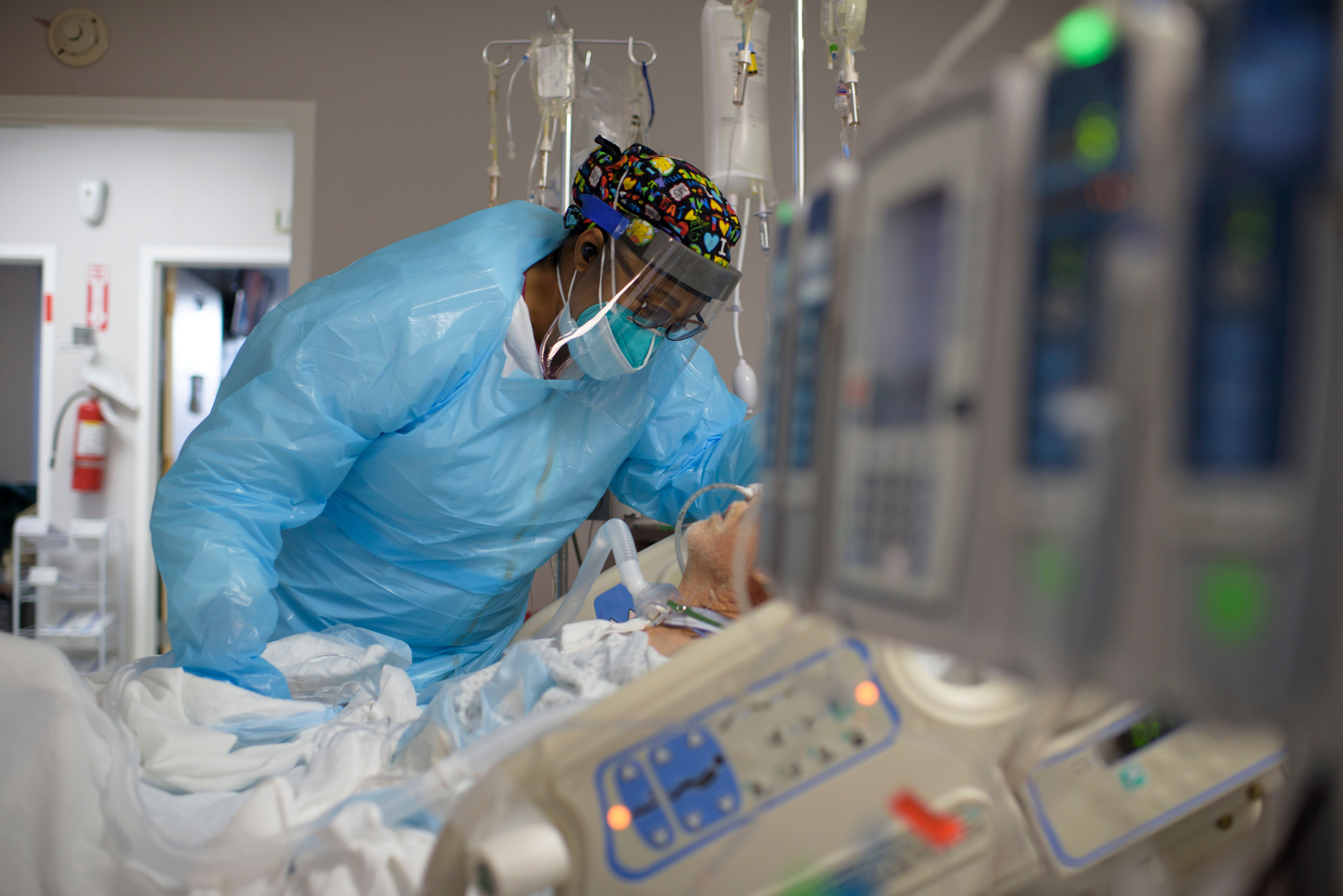 A health care worker comforts a COVID-19 patient in Houston.