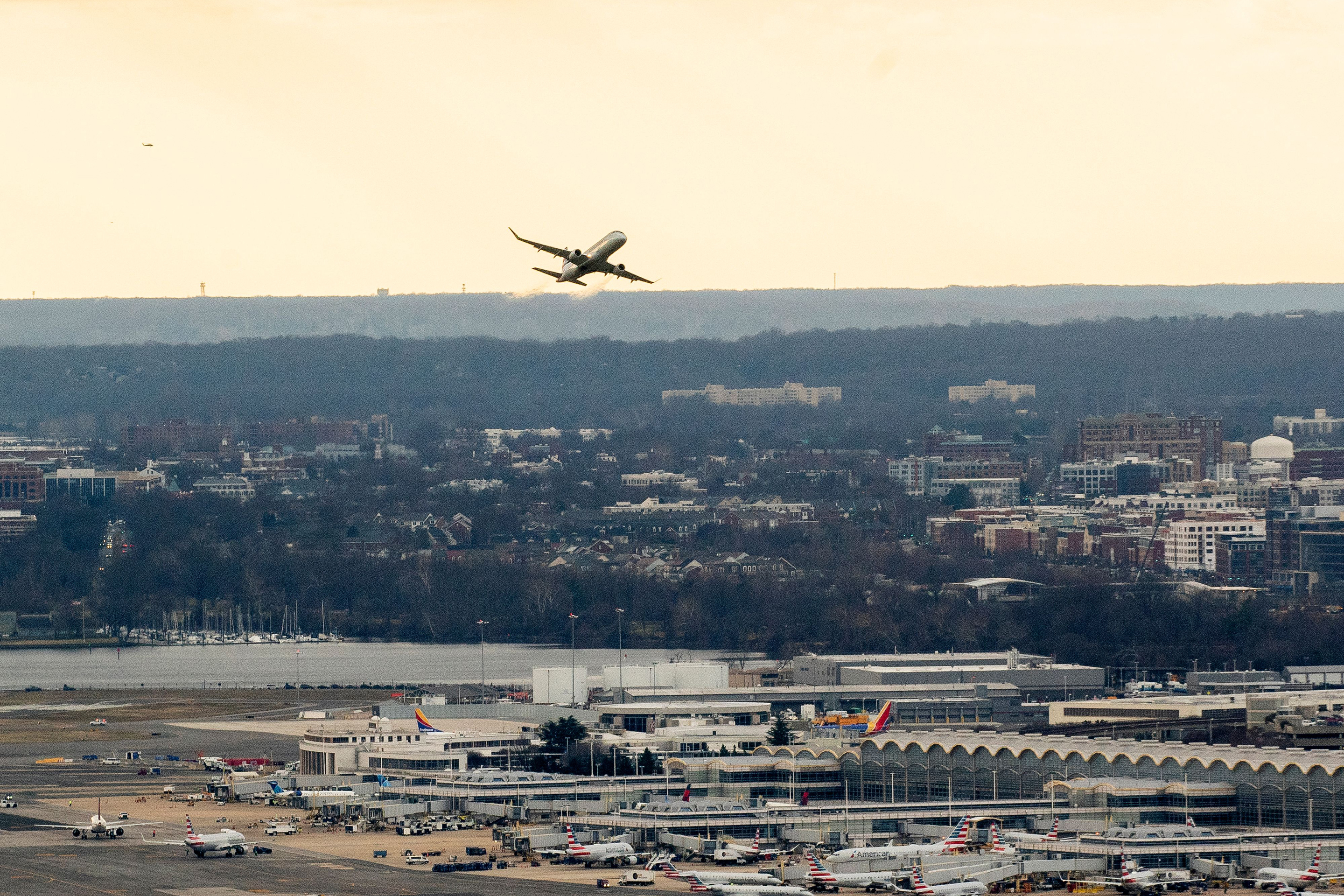 A passenger aircraft takes off from Ronald Reagan National Airport in Arlington, Virginia, on January 18, 2022, as seen from Washington, DC. - The chief executives of the largest US airlines warned of a "catastrophic disruption" to travel and shipping operations if telecommunication firms roll out their 5G technology as planned on January 19 without limiting the technology near US airports. Verizon and AT&T have already twice delayed the launch of their new C-Band 5G service, due to warnings from airlines and aircraft manufacturers concerned that the new system might interfere with the devices planes use to measure altitude.