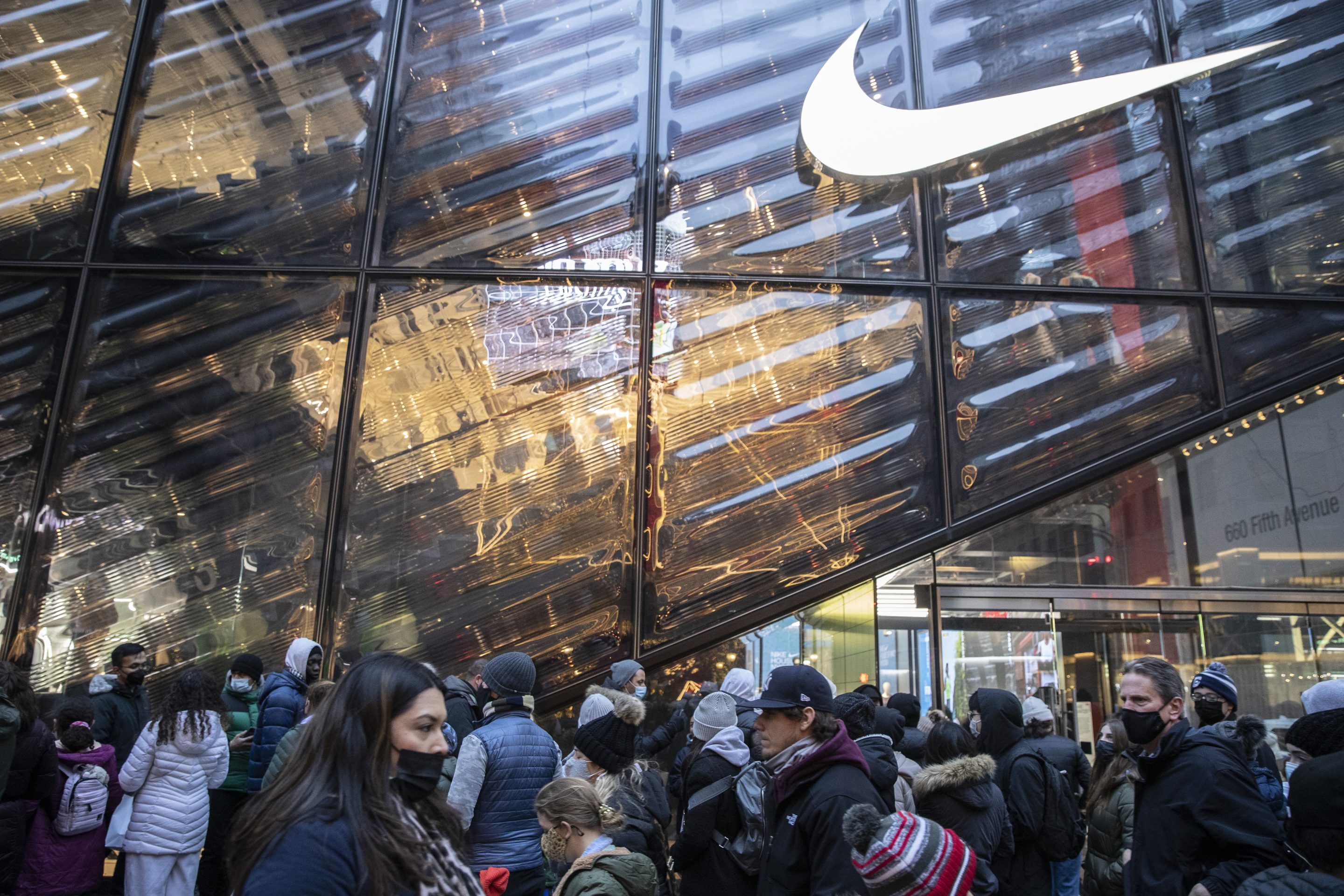 Shoppers wait in line at a Nike store on Fifth Avenue in New York, U.S., on Monday, Dec. 27, 2021. U.S. holiday sales jumped 8.5% from last year as consumers spent more money on clothes, jewelry and electronics, a report from Mastercard SpendingPulse showed. Nike filed a complaint against shoe and apparel exchange StockX last week.