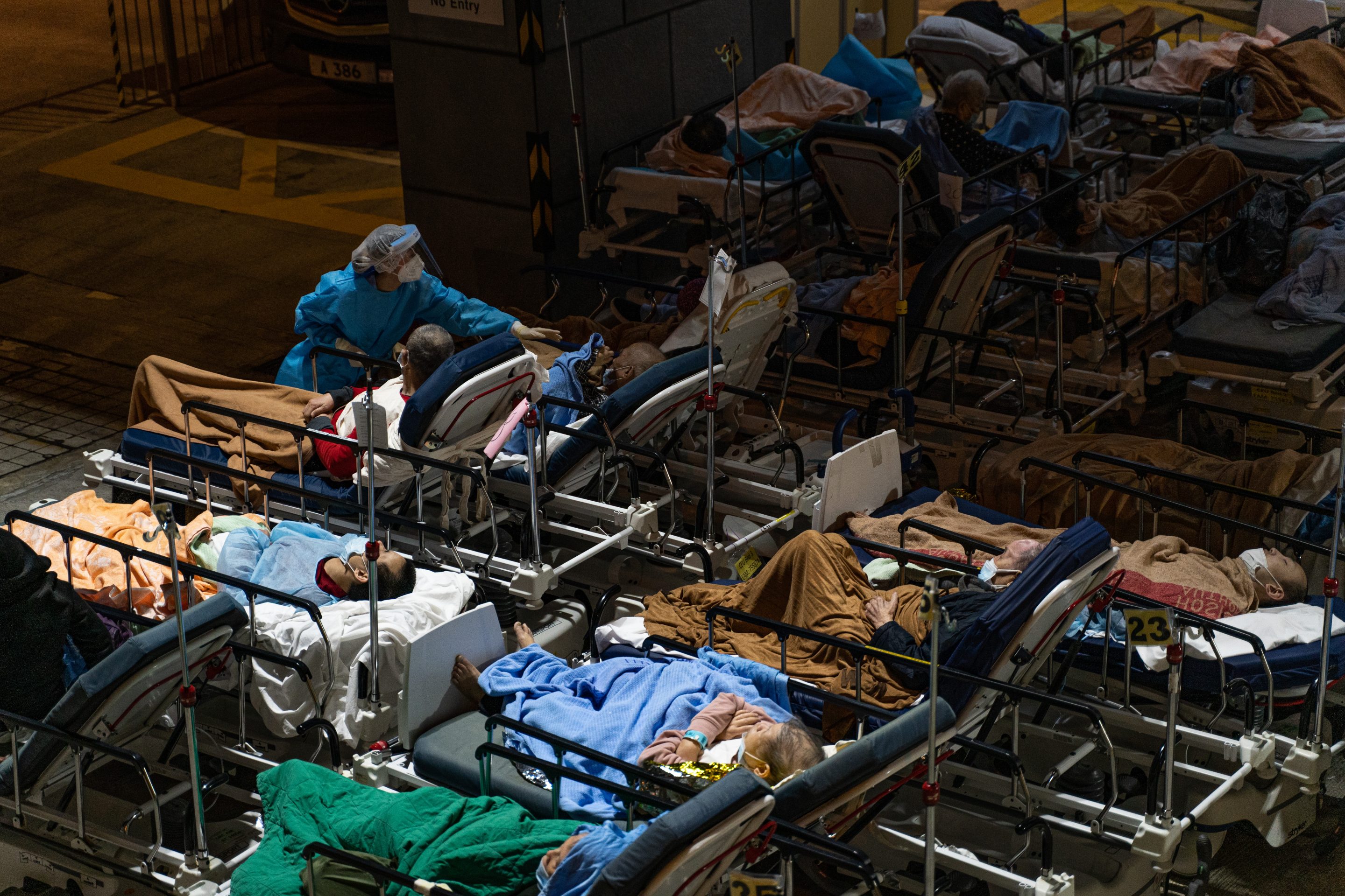 COVID patients in Hong Kong lie in beds outside while being treated by a doctor wearing personal protective equipment