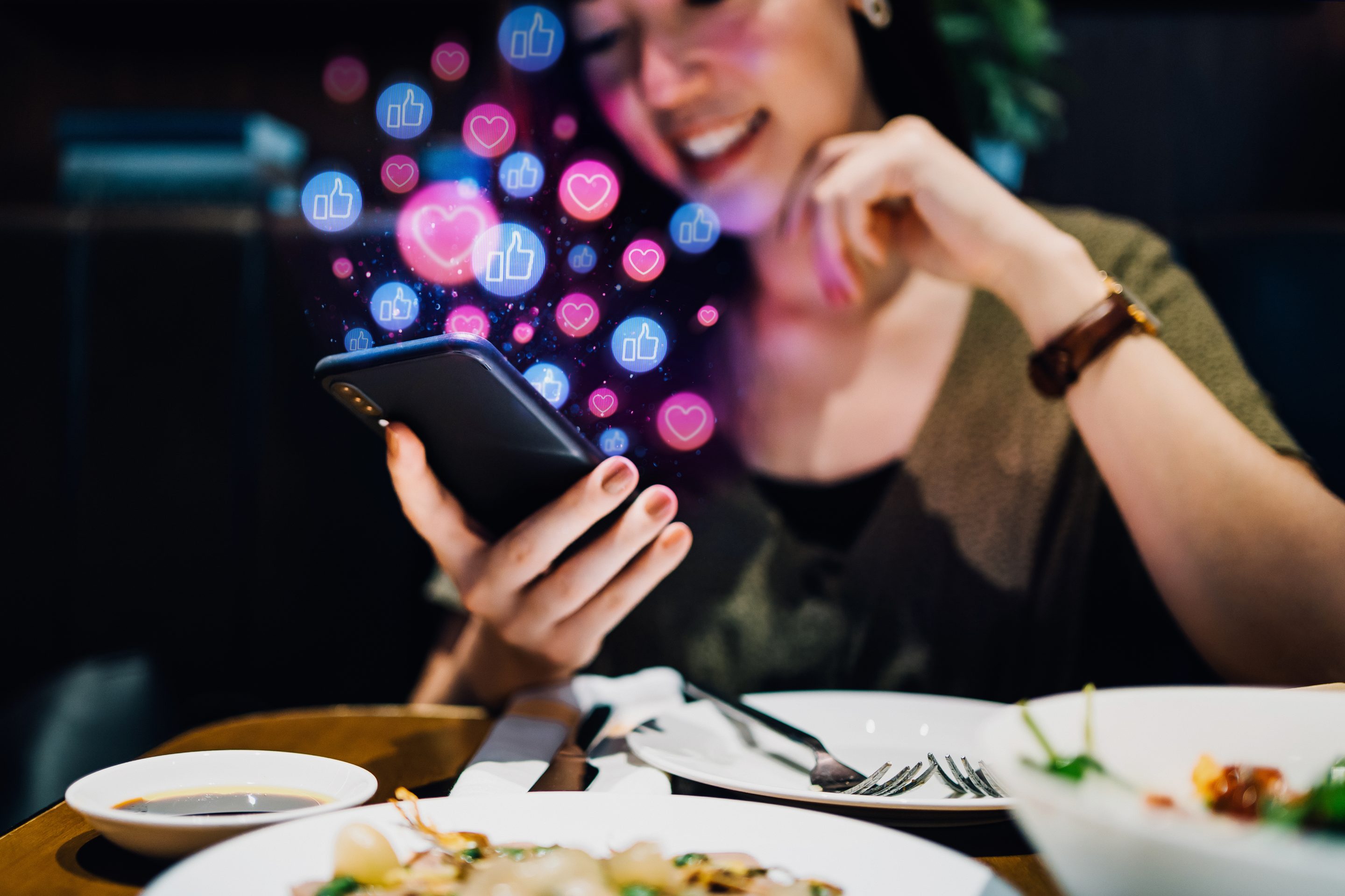 A young woman on social media using her smartphone while at a restaurant.