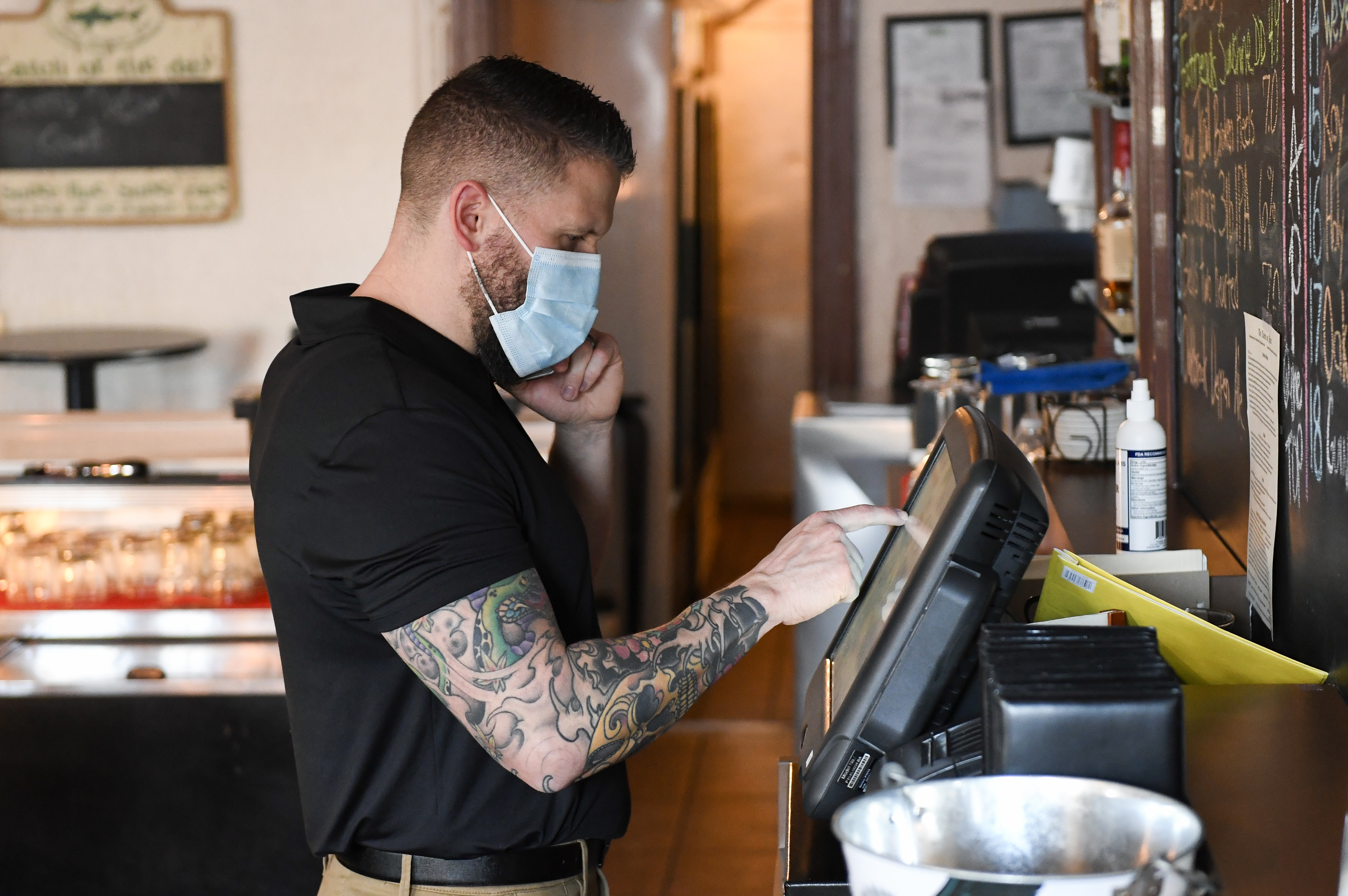 Travis Mosser, co-owner of Tavern on Penn, in West Lawn, Pa., takes an order from a customer over the phone, on March 10, 2021. Like other restaurants the tavern has had to adapt to challenges and restrictions over the past year during the COVID-19 pandemic.