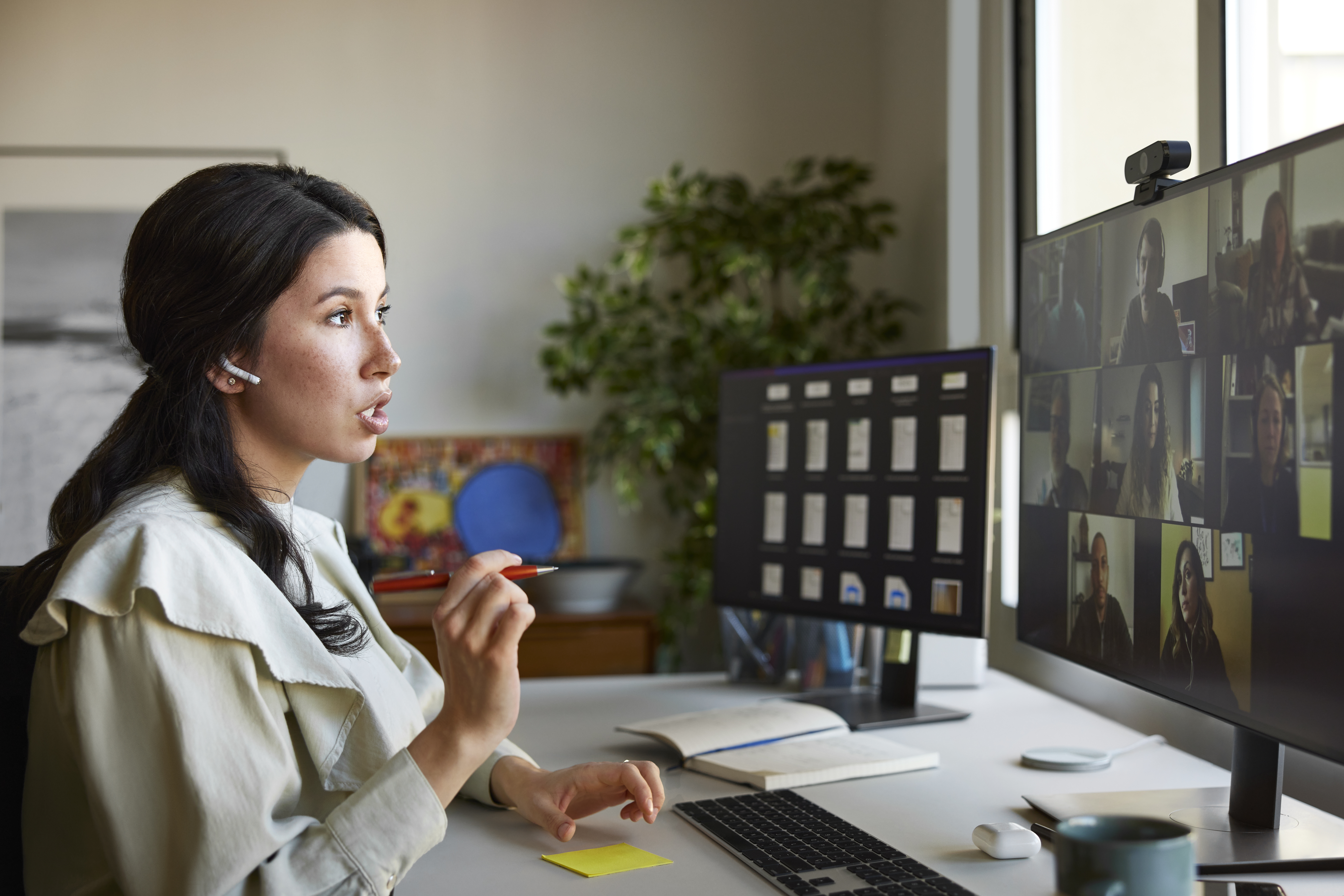 Businesswoman gesturing during video conference with colleagues. Female professional is using computer at desk. She is in home office.