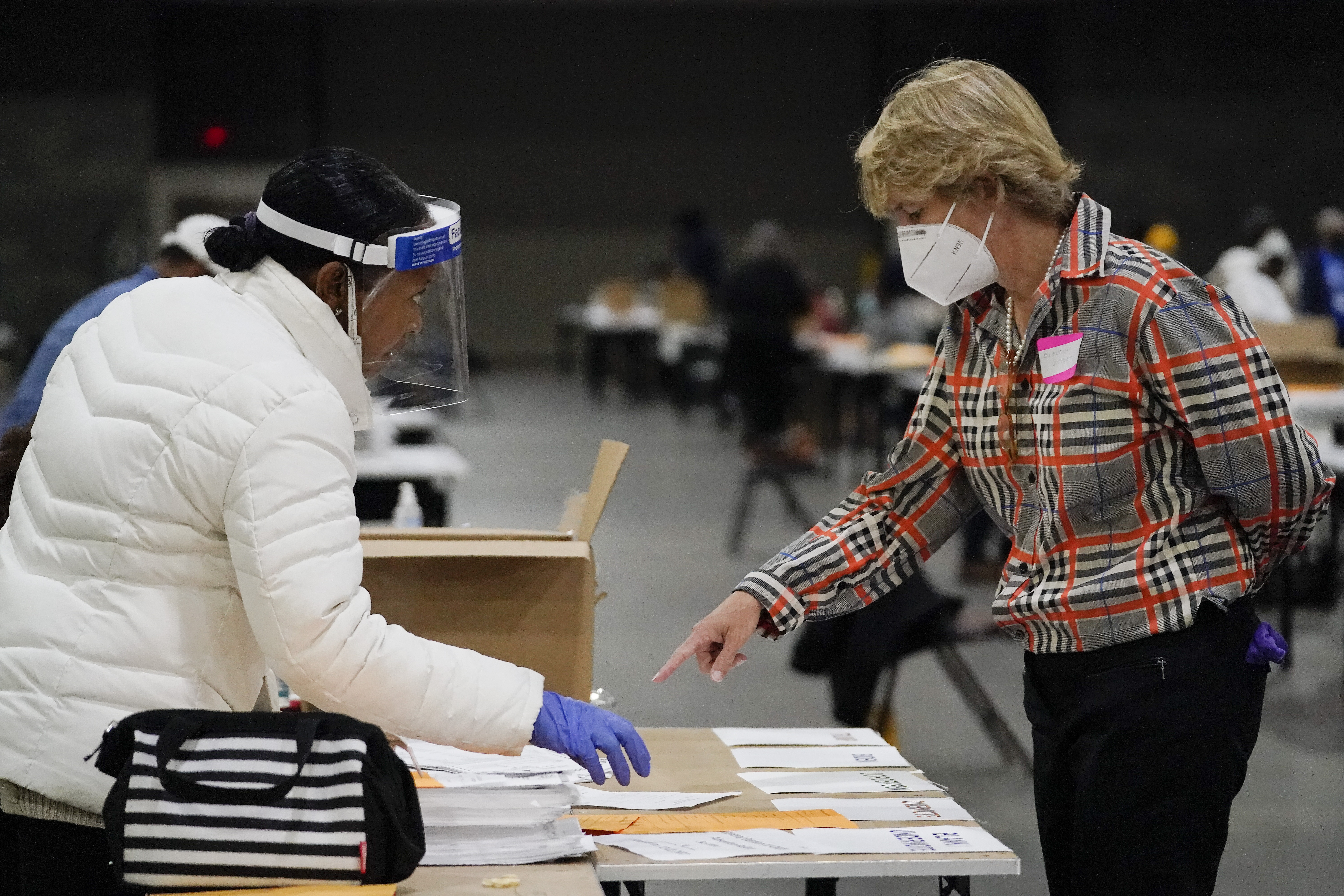 FILE - An election official helps another as they sort ballots during an audit at the Georgia World Congress Center on Nov. 14, 2020, in Atlanta. Republican lawmakers in at least six states have introduced legislation that would require all ballots to be counted by hand instead of electronic tabulators, and similar proposals are being floated in some county and local governments.