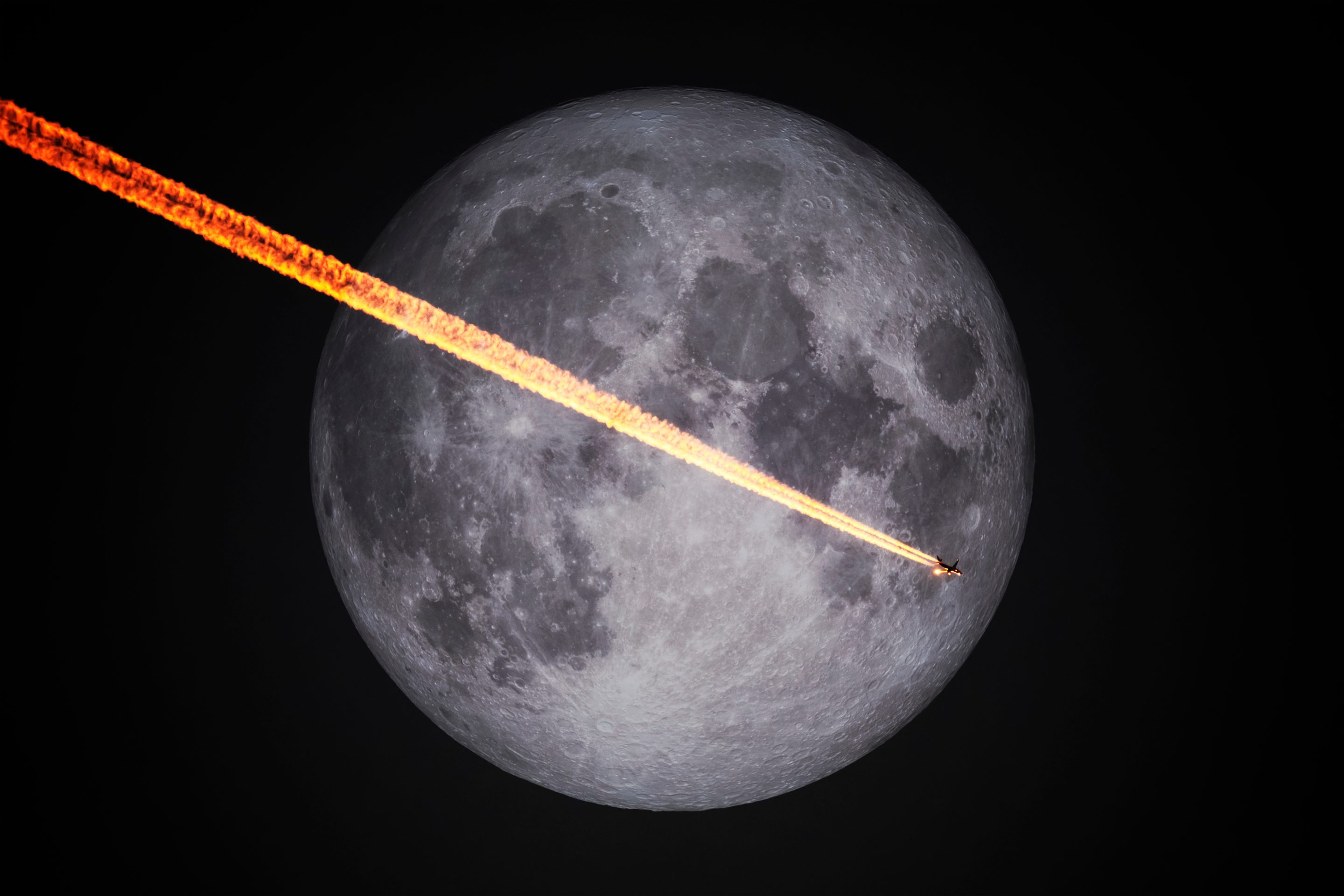 A plane flies in front of a full moon in the night sky.