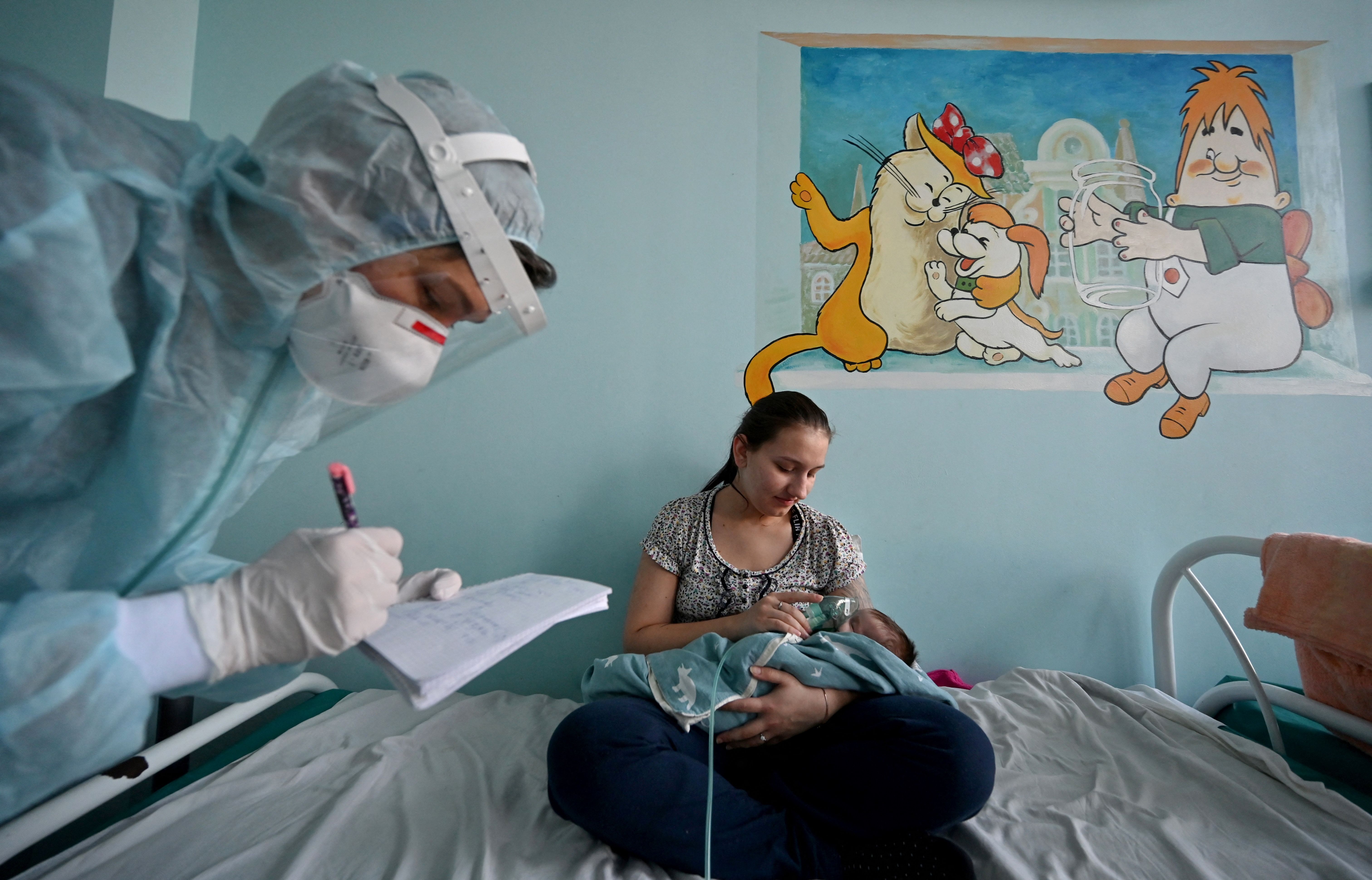 A woman holds an oxygen mask over the face of her baby suffering from COVID in a ward of a children's hospital in Kiev on Nov. 16, 2021. 