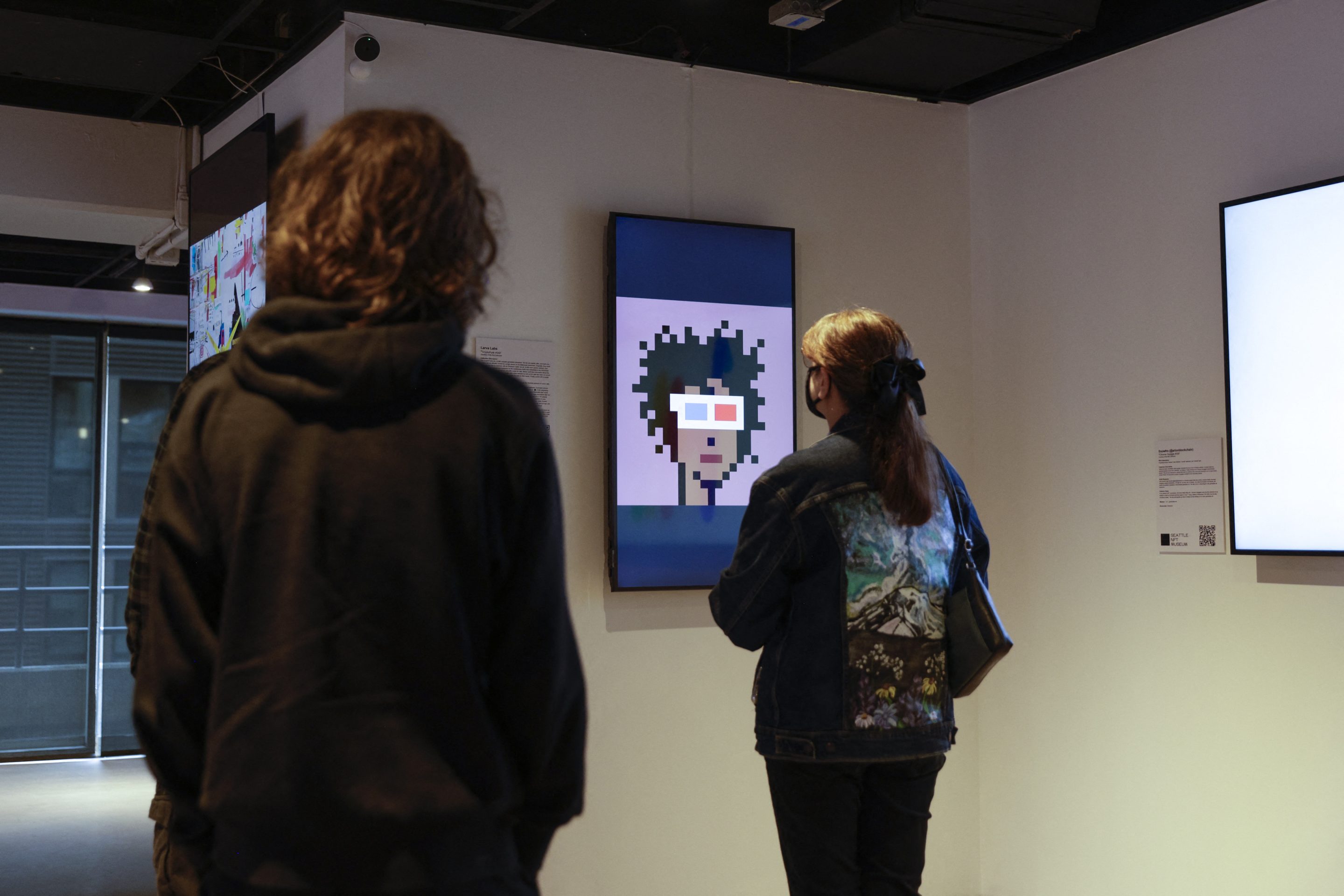 Visitors view the digital art piece "CryptoPunk #553" by Larva Labs during the opening weekend of the Seattle NFT Museum in Seattle, Washington on January 29, 2022. - Using the blockchain technology behind cryptocurrencies, Non-fungible tokens (NFTs) transform anything from illustrations to memes into virtual collectors' items that cannot be duplicated.