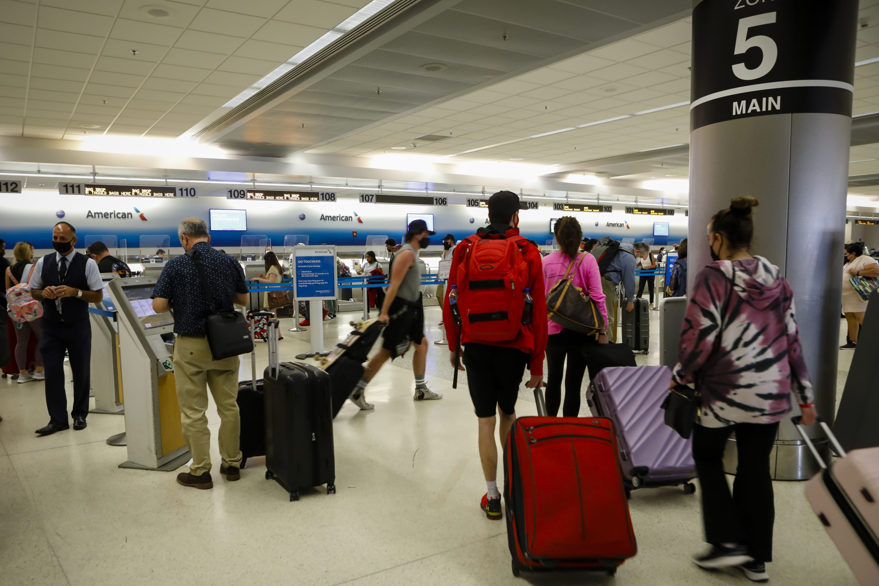 Travelers arrive at the American Airlines check-in counter