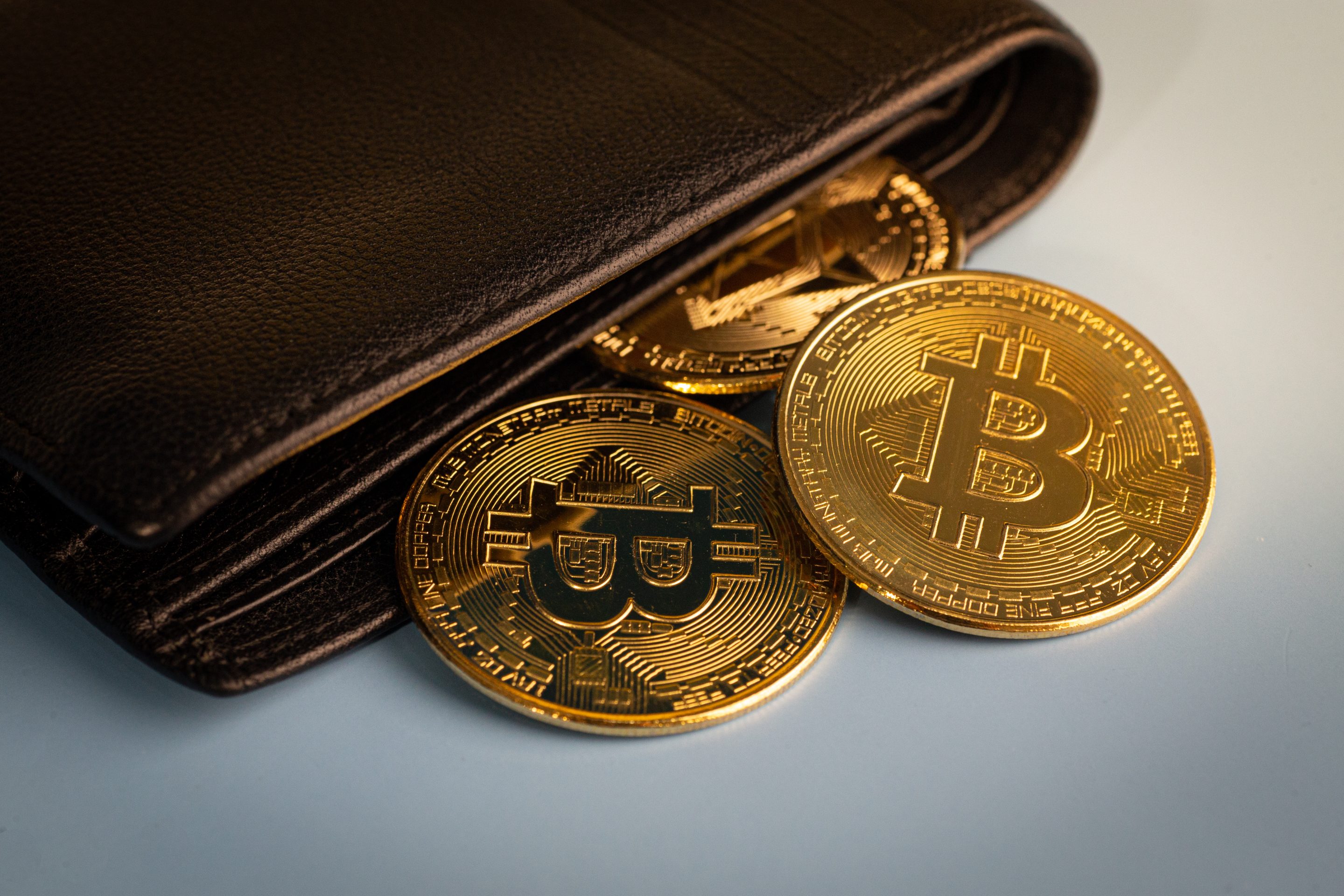 Golden Bitcoin token falling out of a wallet.
