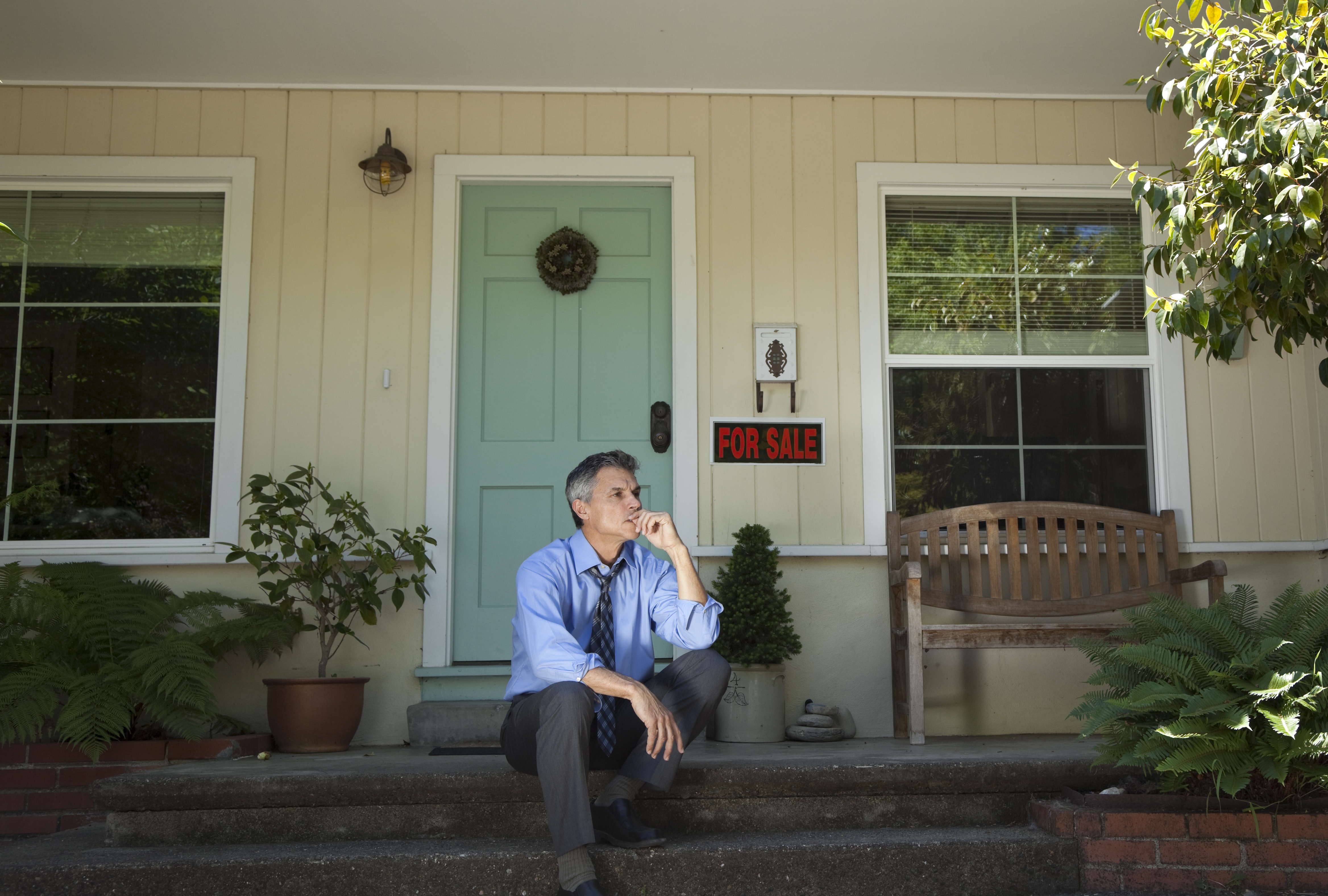 Man sits on the porch of his home
