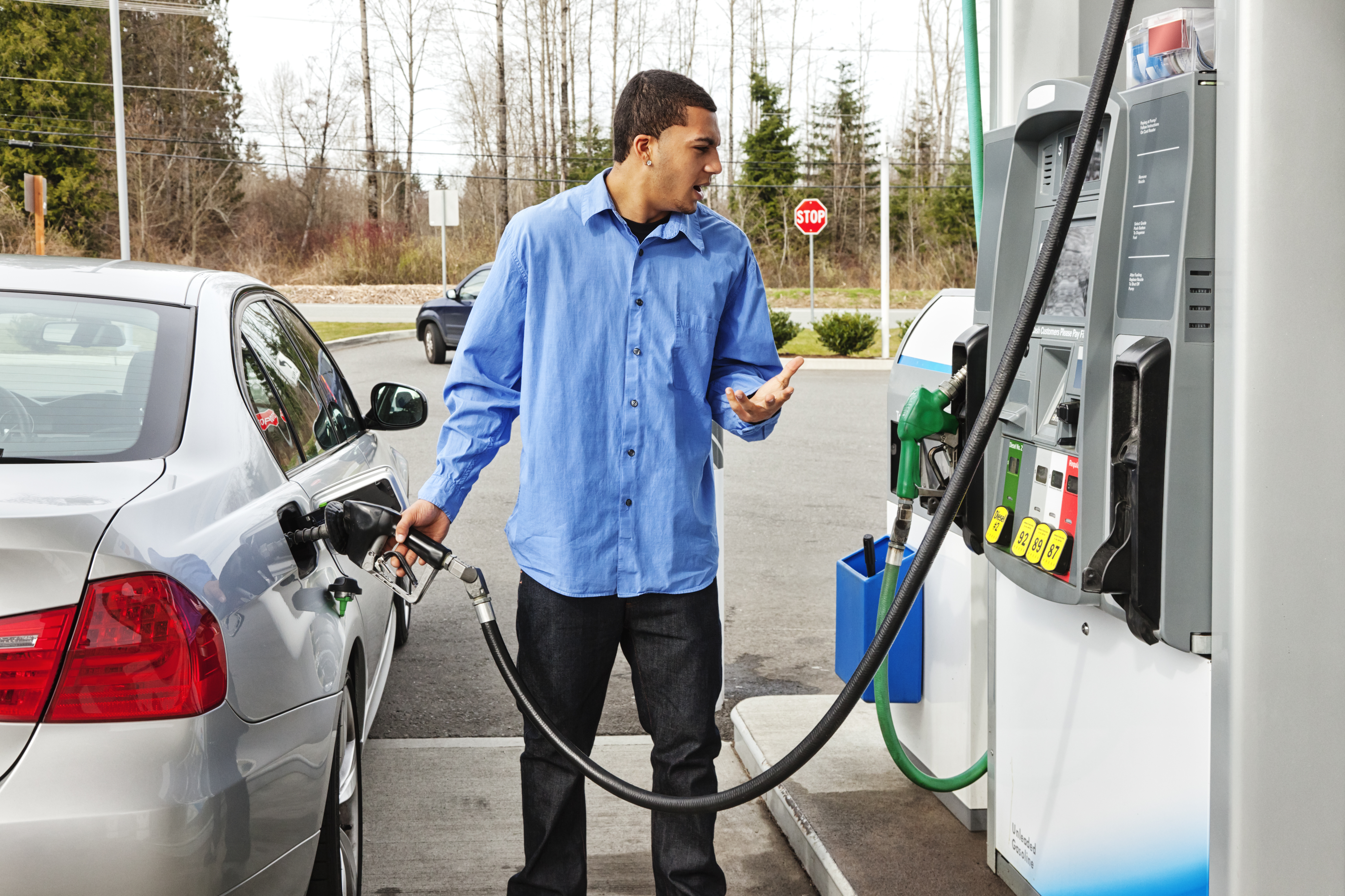 A stock photo of a young man filling up his gas tank.