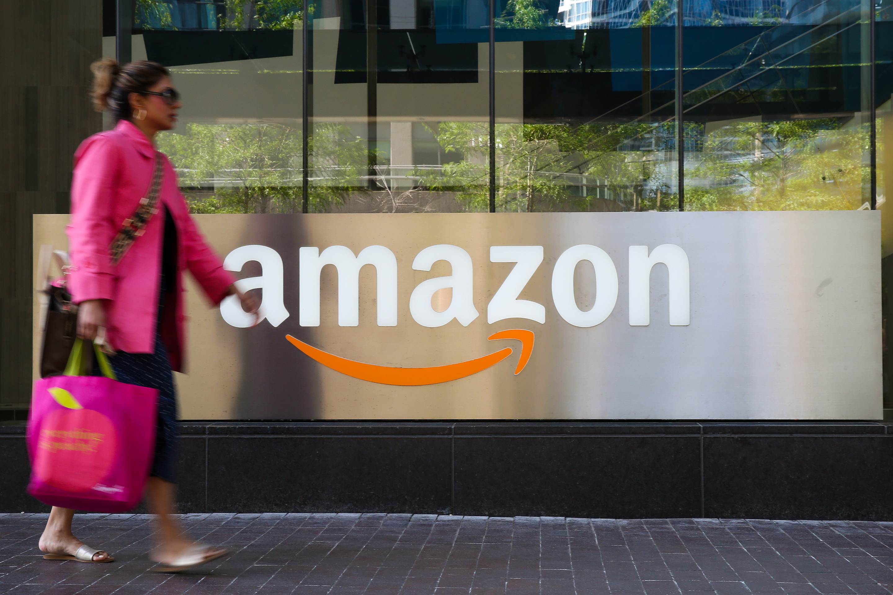 Woman walks past Amazon logo in Toronto.