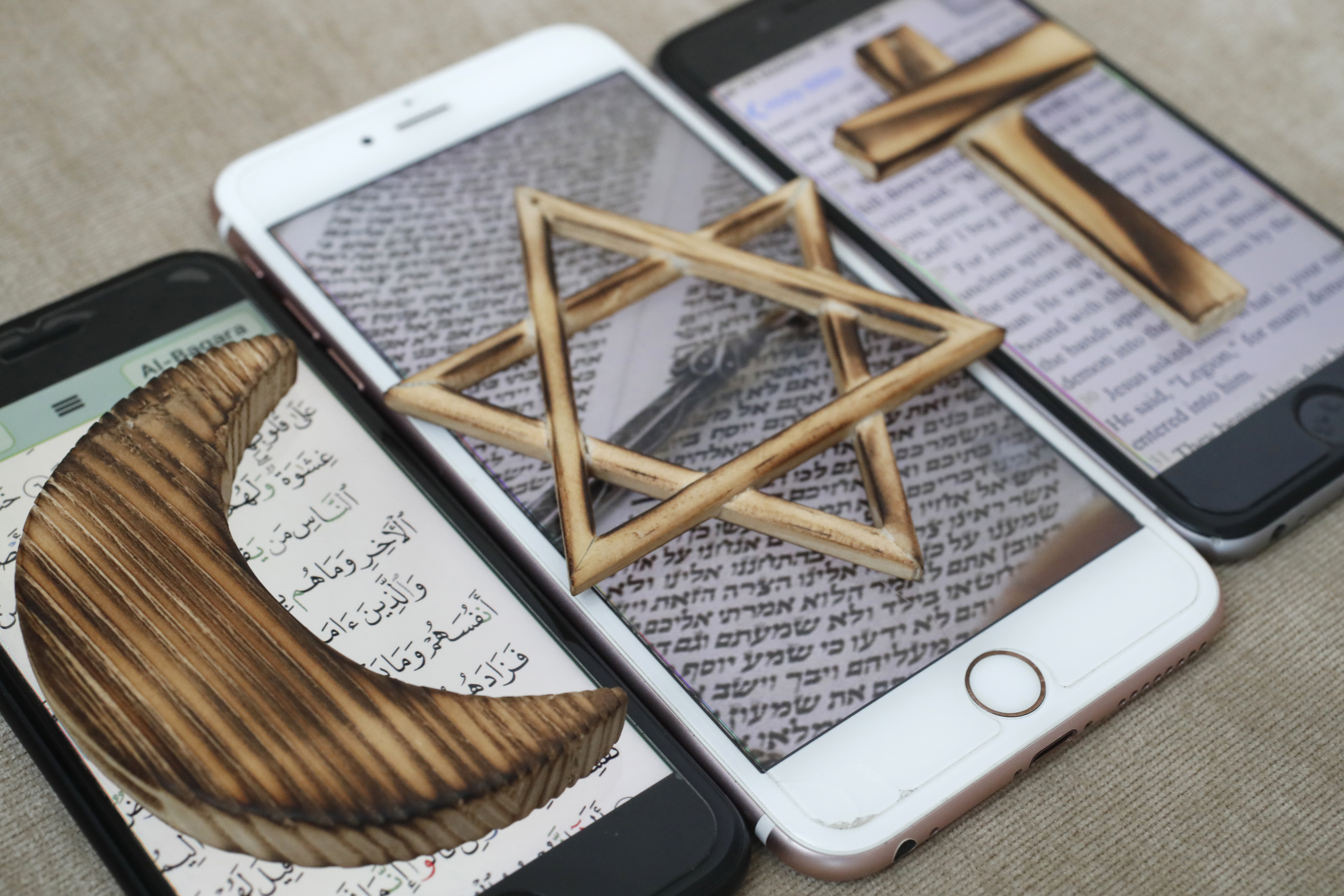 A Jewish Star, Christian Cross and and Muslim Crescent, religious symbols of Christianity, Islam, Judaism set on 3 smartphones with digital app.
