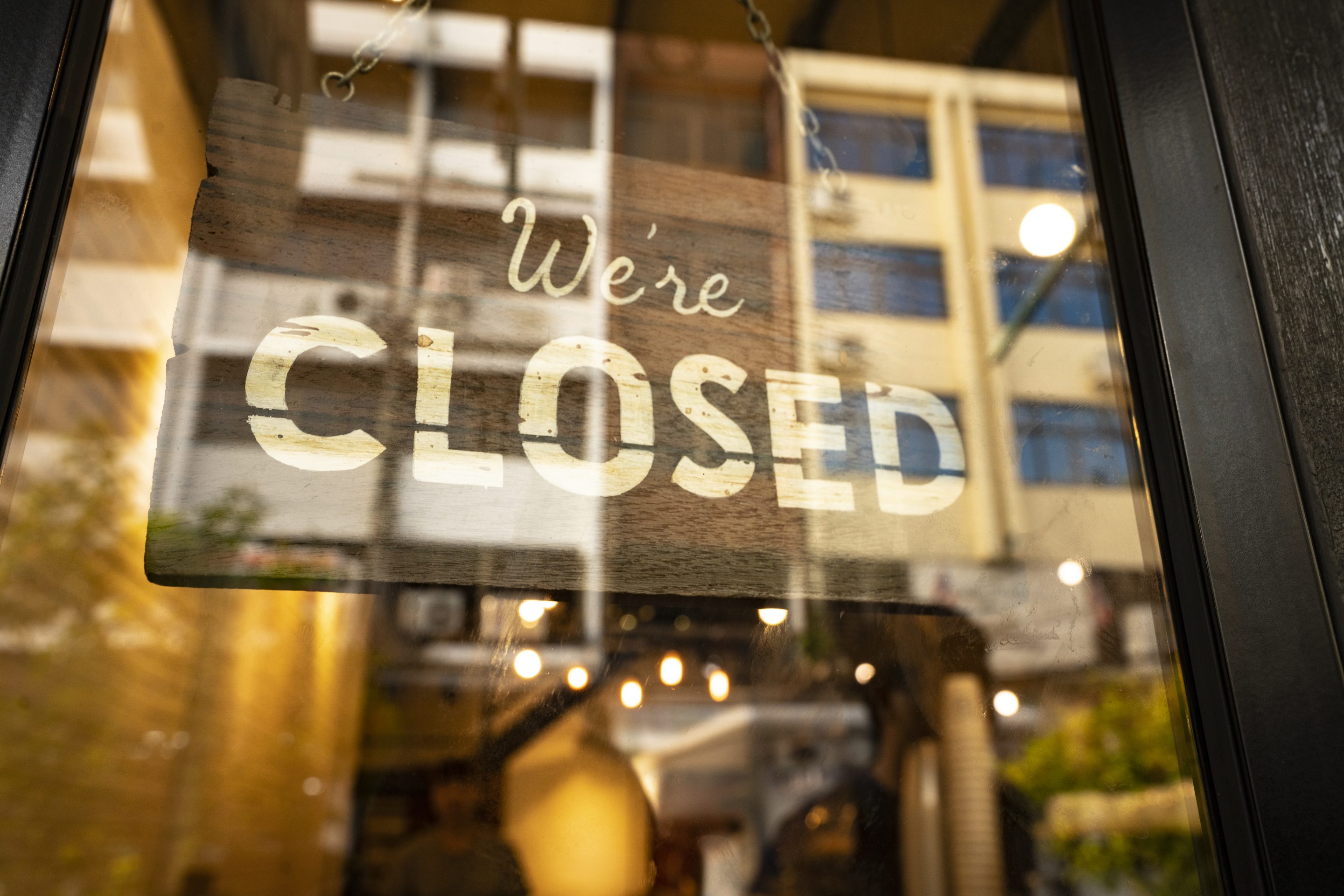A “closed” sign hanging in a window