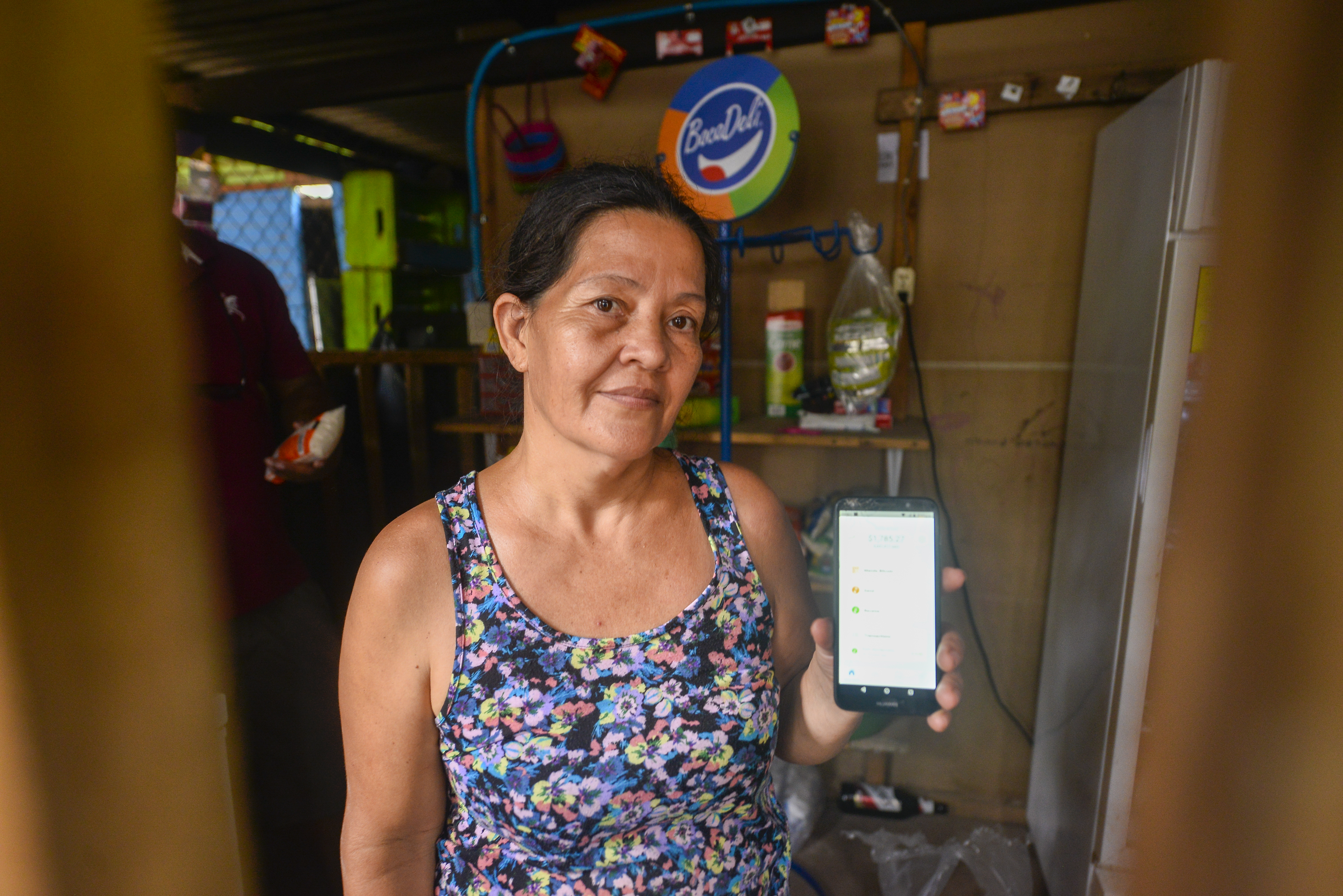 A woman holds up a phone displaying a bitcoin wallet app on June 16, 2021, in Chiltuipan, El Salvador. Playa El Zonte has been named as the Bitcoins capital, around 500 families promote the use of the cryptocurrency to help the economy of a place with poverty issues.