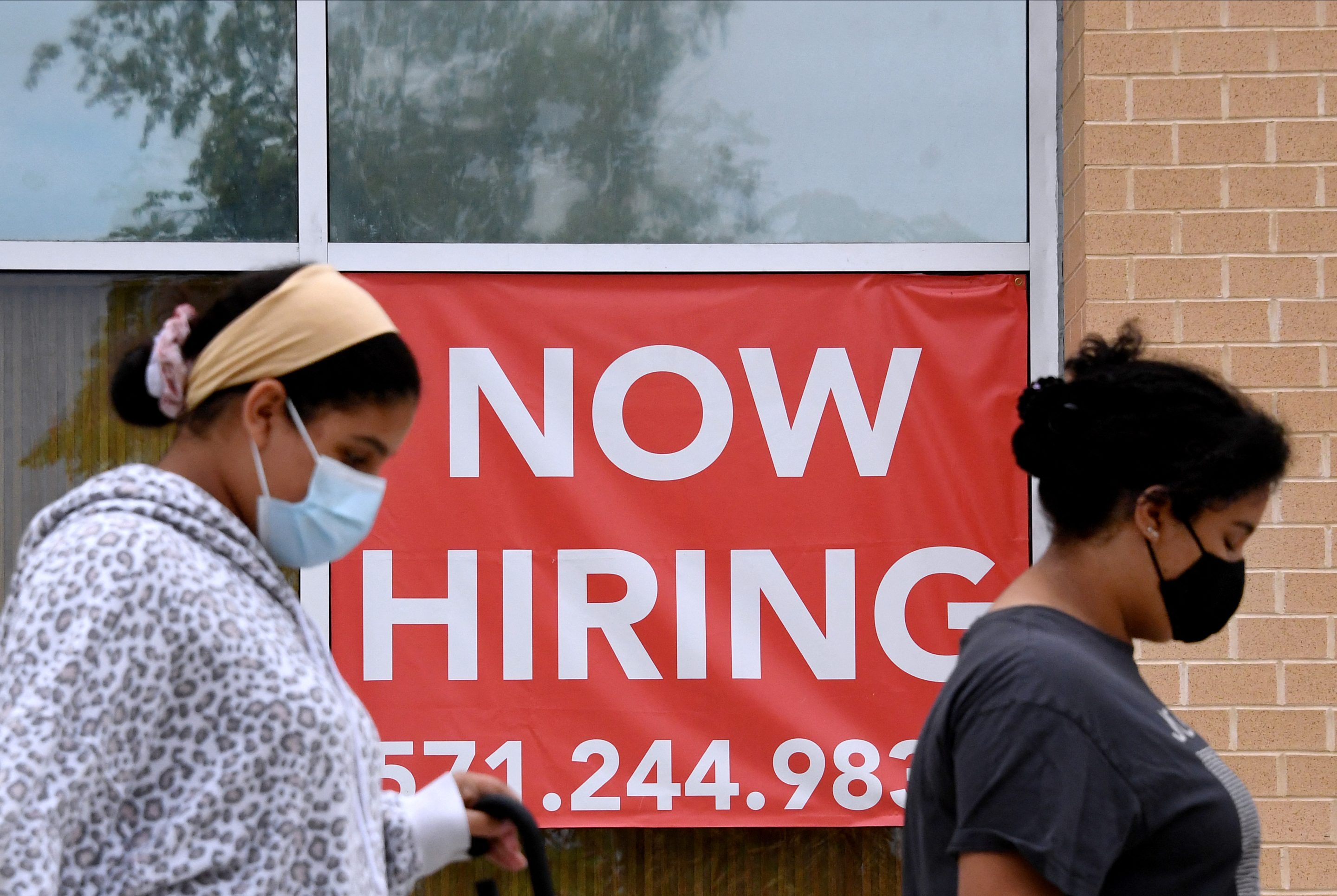 Women walk past by a "Now Hiring" sign outside a store on August 16, 2021 in Arlington, Virginia. The U.S. added 431,000 jobs in March, according to the Labor Department's report.