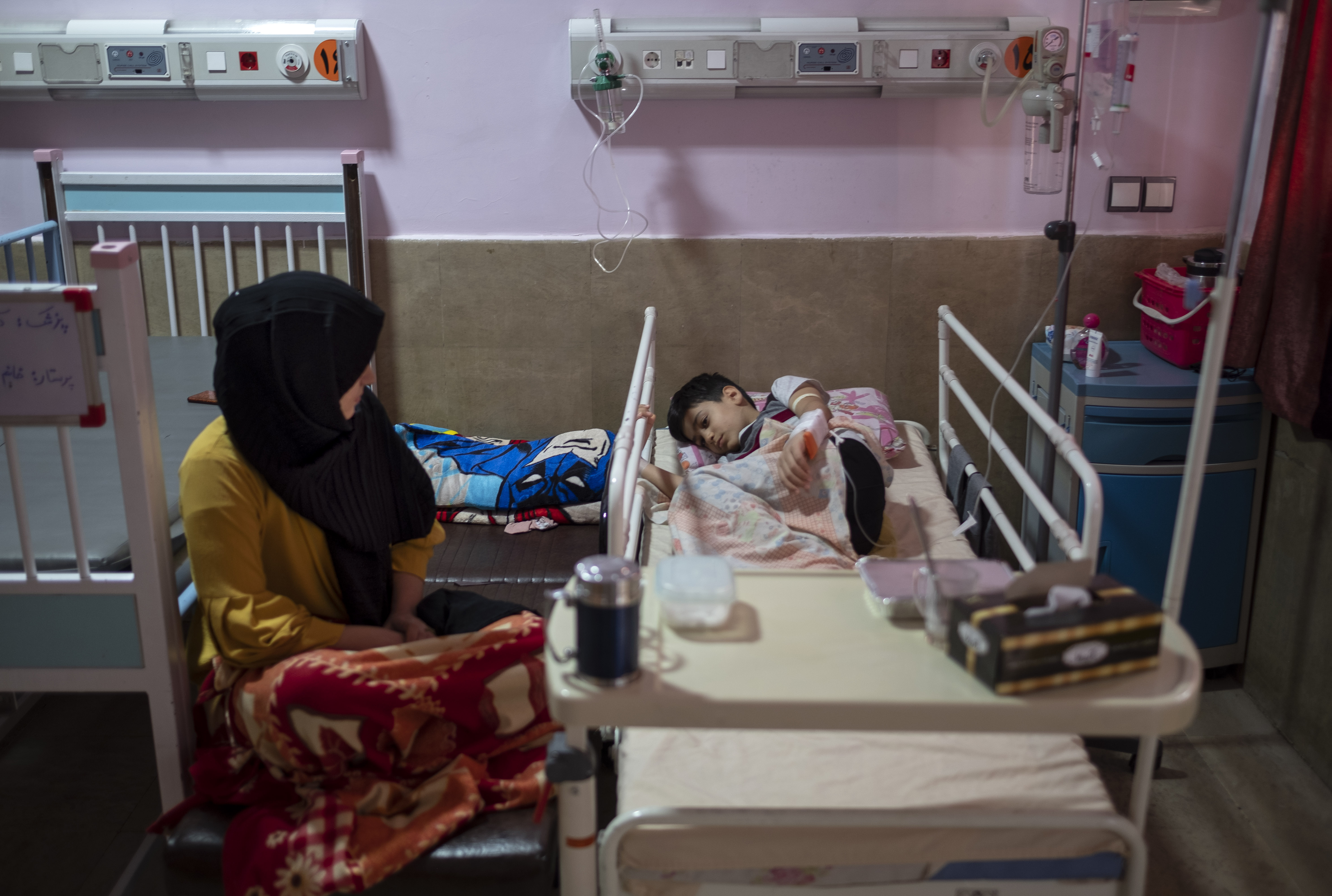 An Iranian mother sits next to her 9-year-old son who is infected by COVID-19, at a COVID-19 ward in a children hospital in the holy city of Qom, south of Tehran, amid the Omicron variant outbreak of the COVID-19 in Iran, March 10.