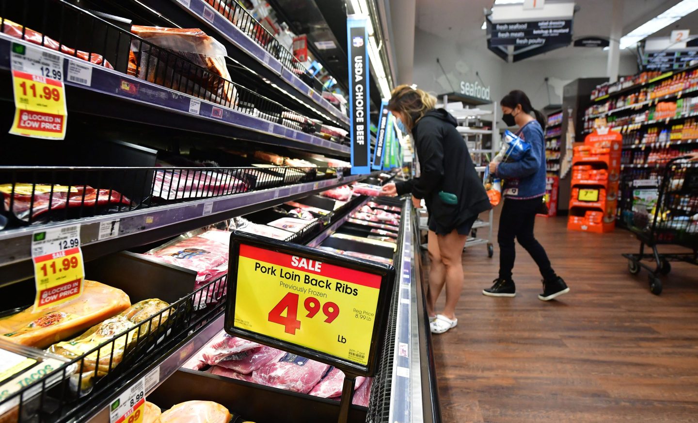 Women looking at beef and pork products at the grocery store
