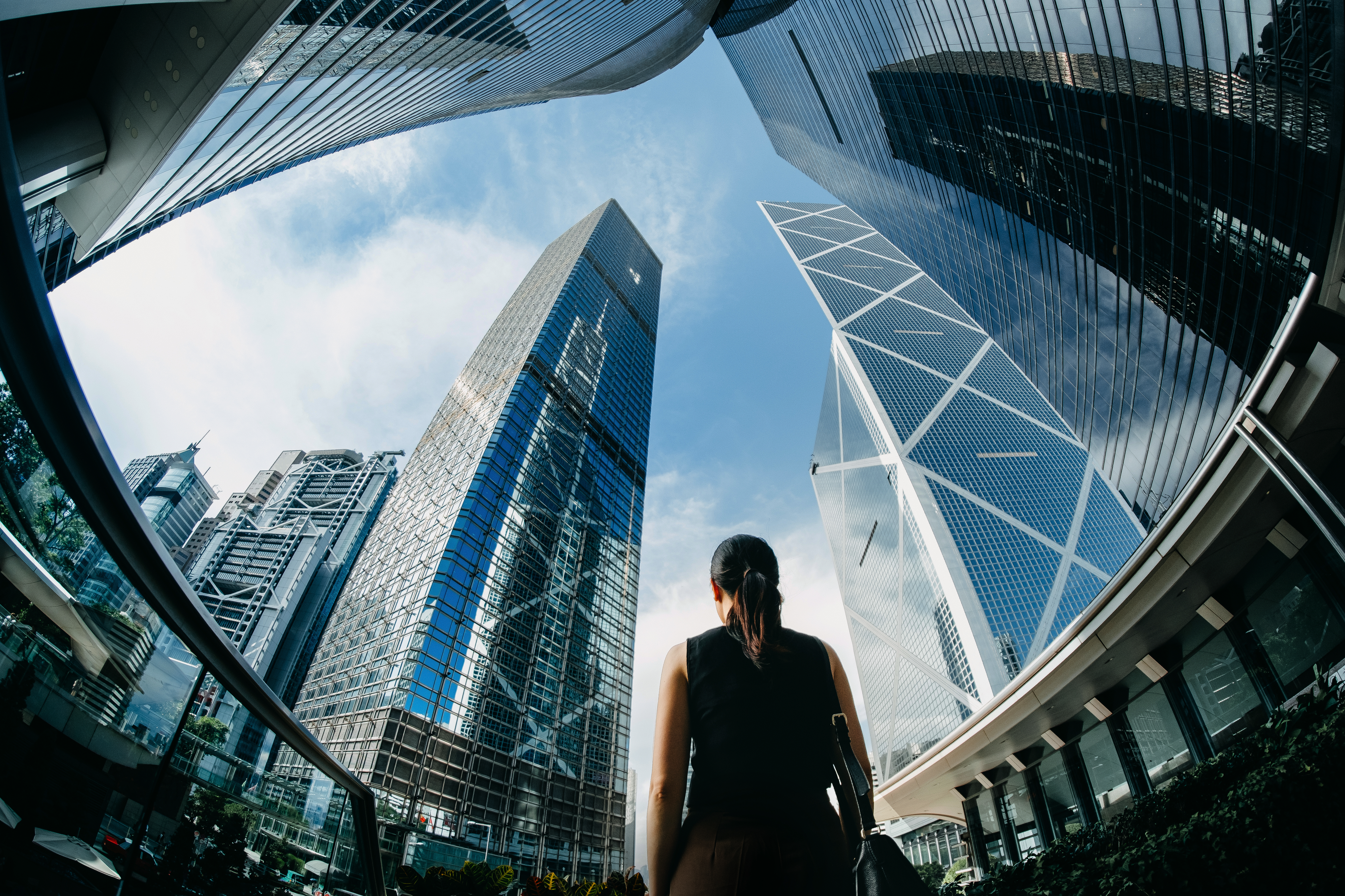 Rear view of professional young businesswoman standing against contemporary financial