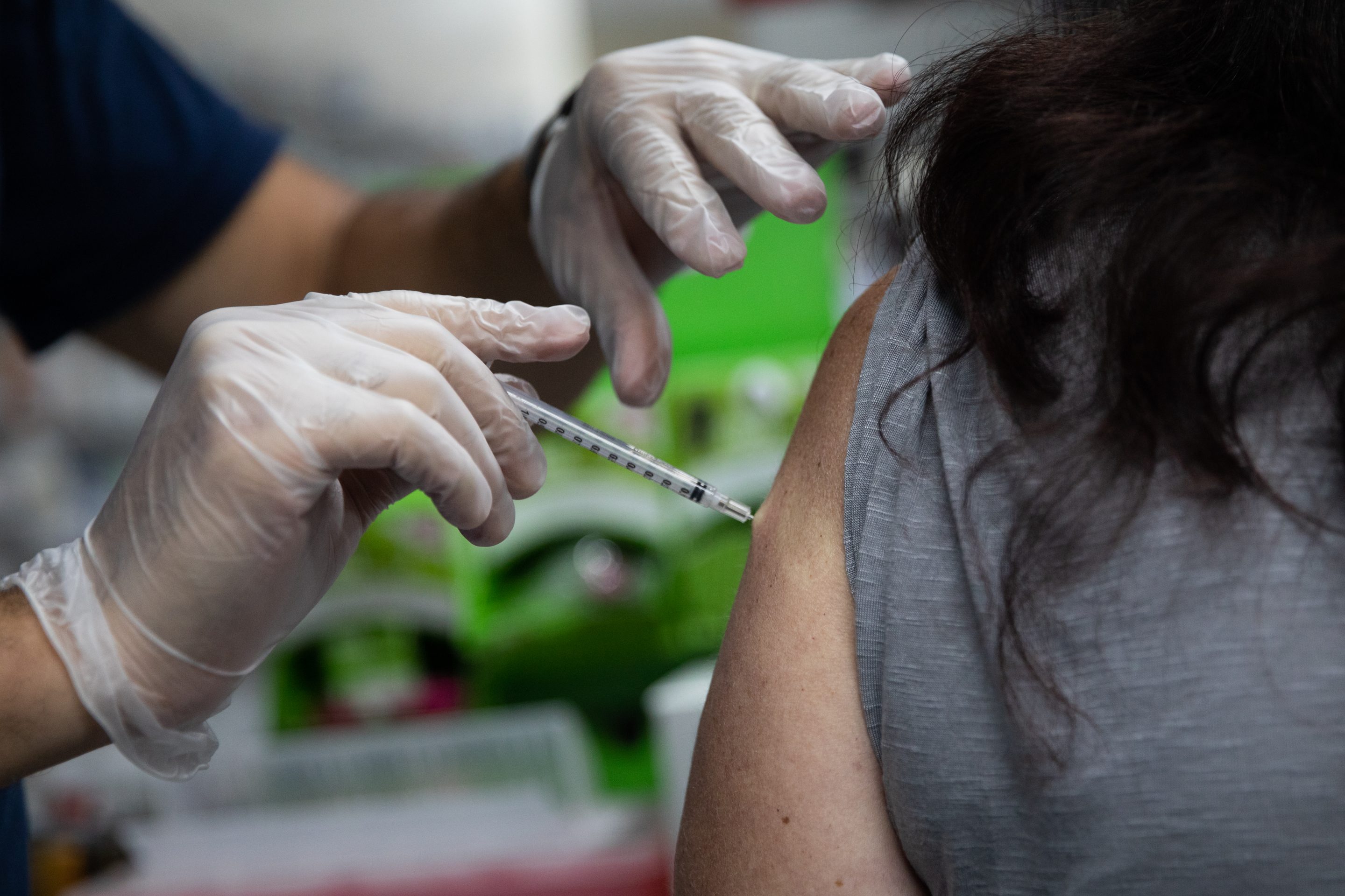 A pharmacist administers a booster shot of Moderna’s COVID-19 vaccine.
