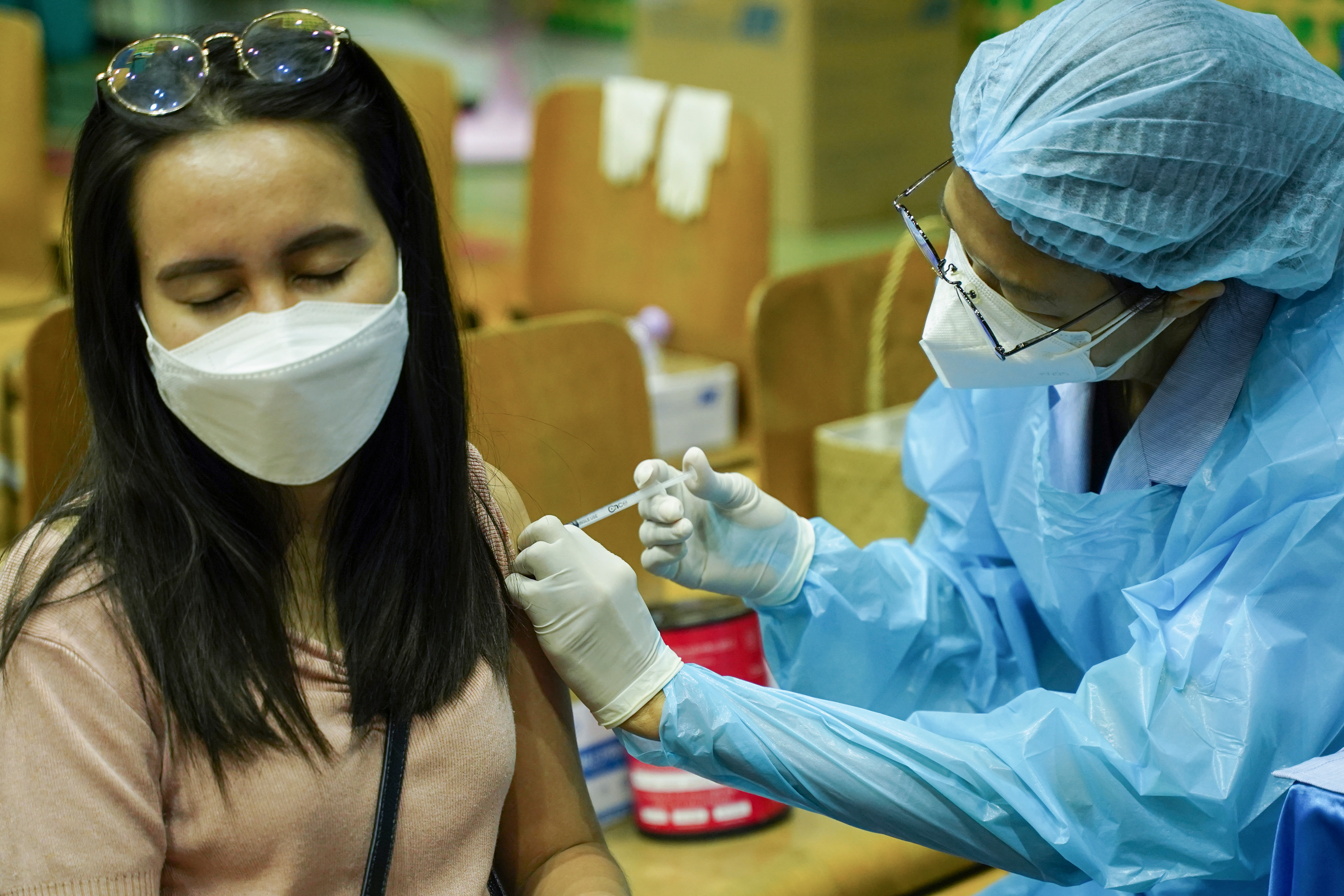 People receive doses of the Pfizer COVID-19 vaccine at a vaccination center inside a stadium in Bangkok, Thailand, 24 February 2022.