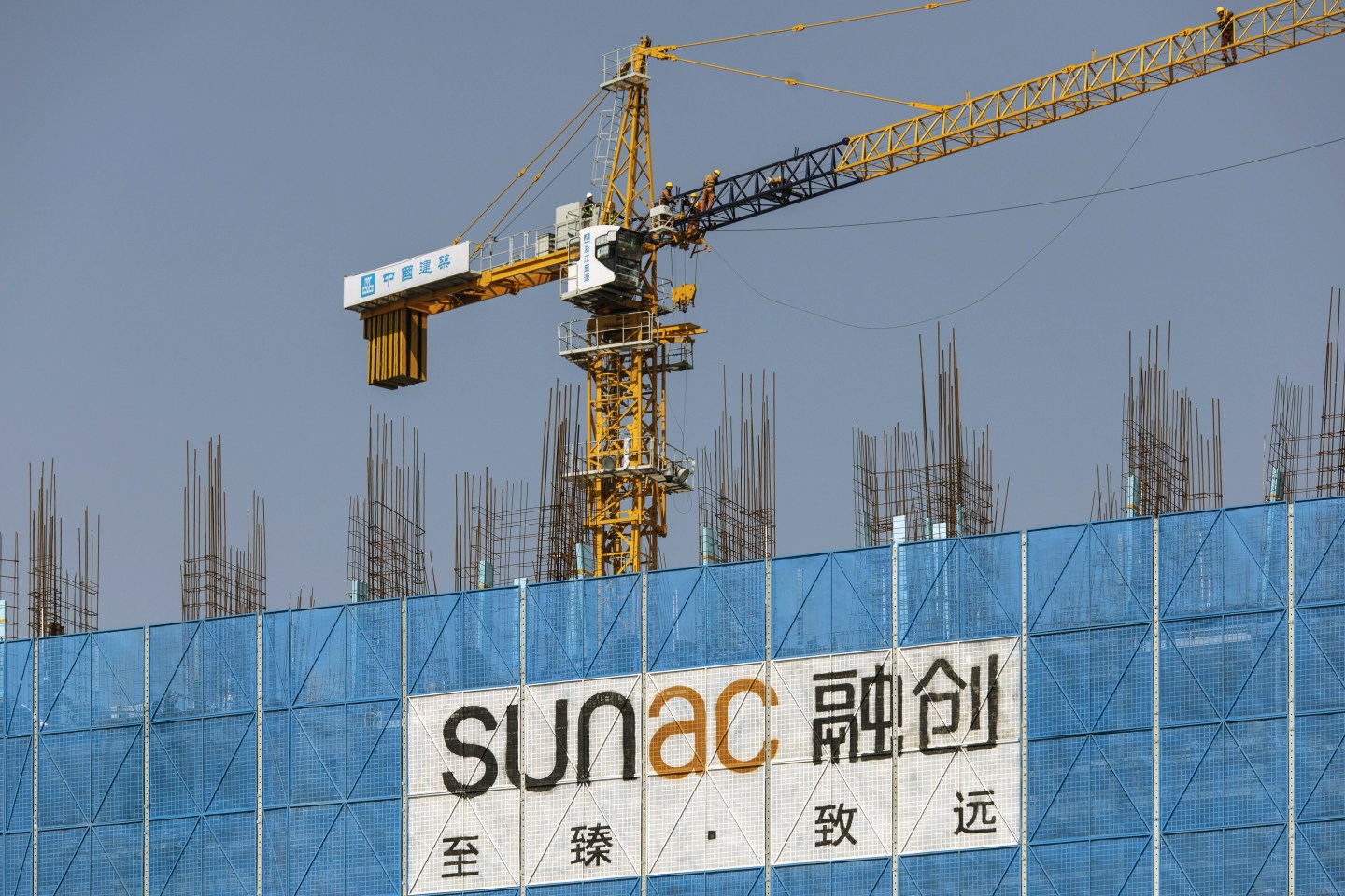 A sign for Sunac hangs from a building under construction