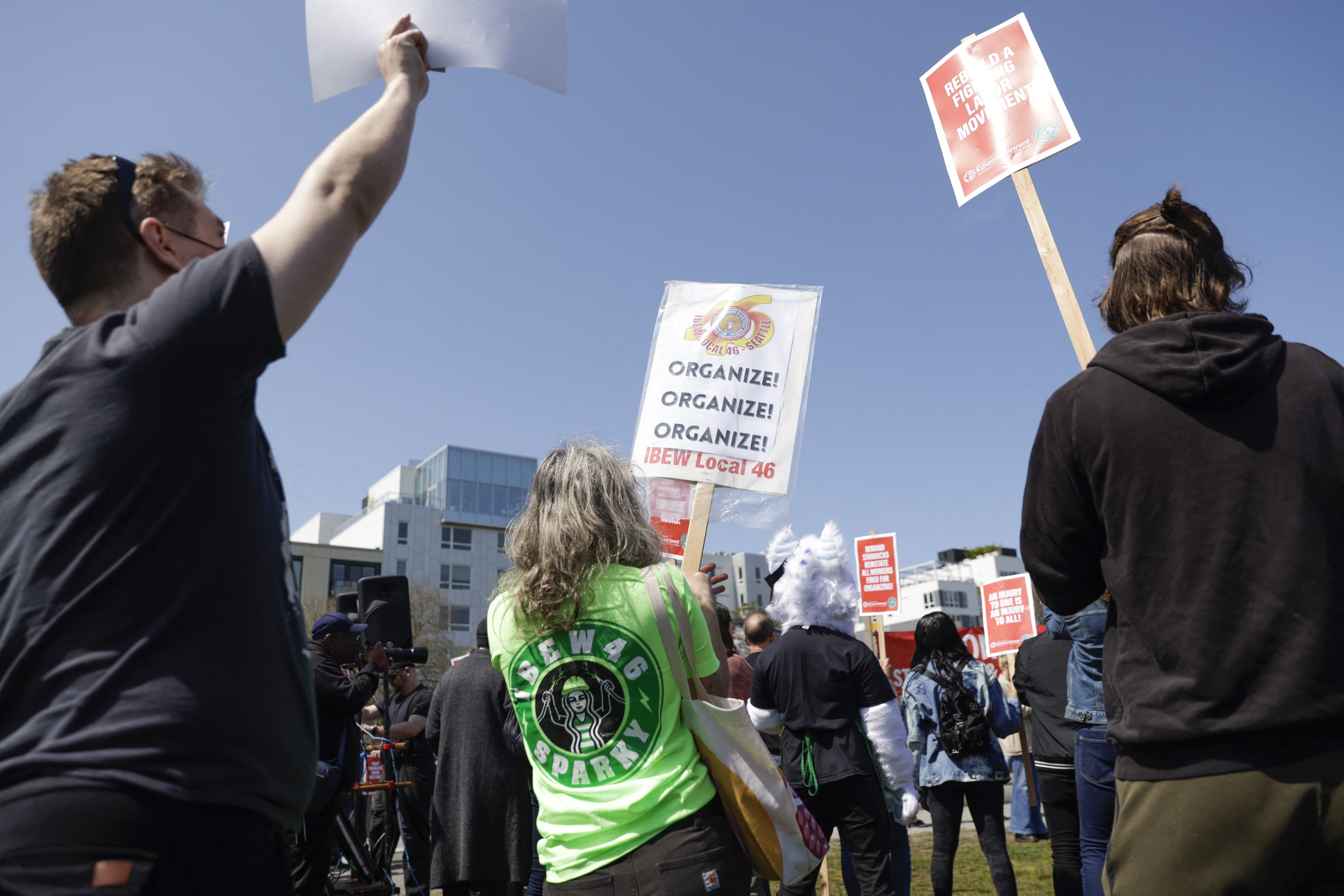 People hold signs during the "Fight Starbucks' Union Busting" rally and march in Seattle.