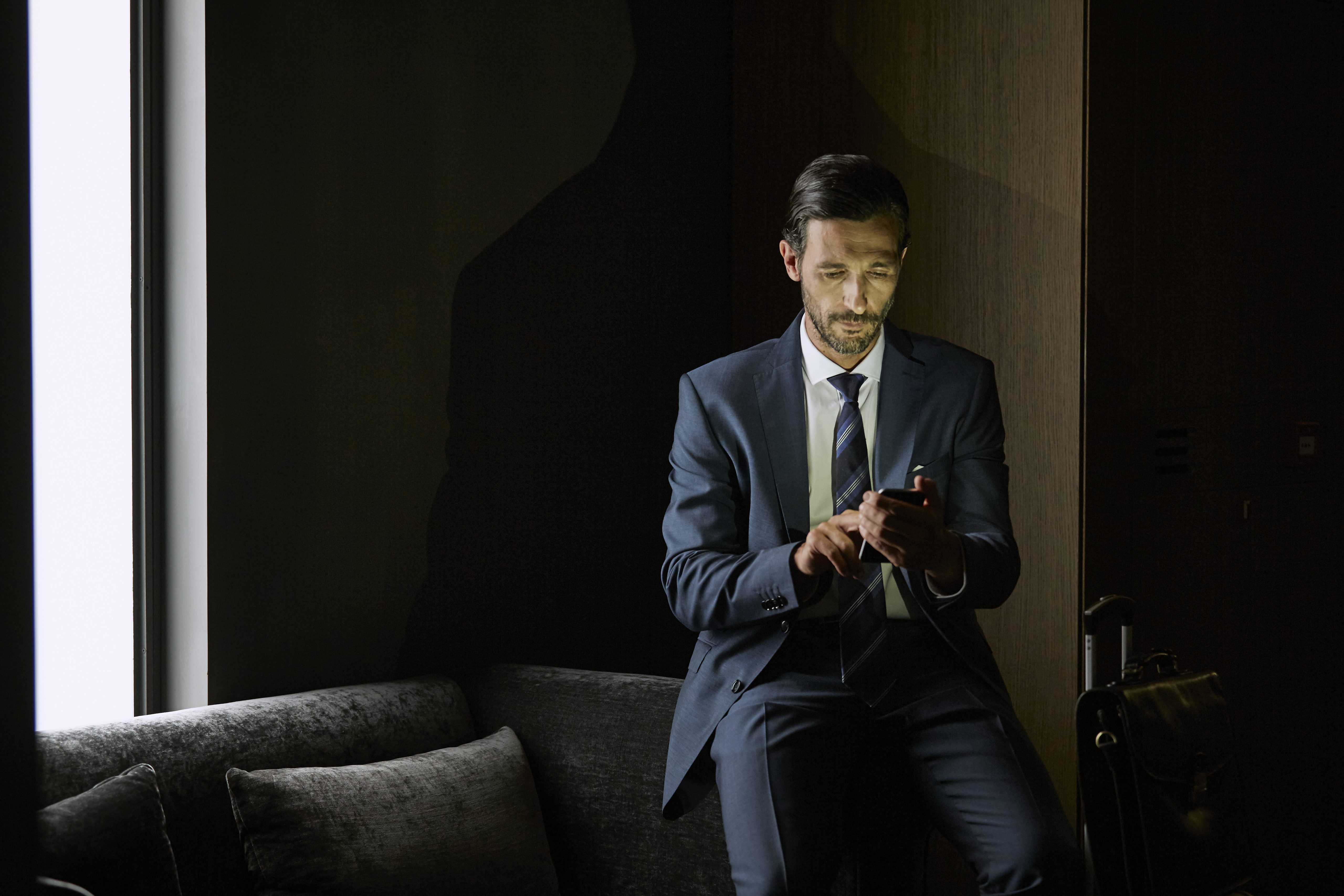 Businessman using mobile phone while sitting on sofa in hotel room