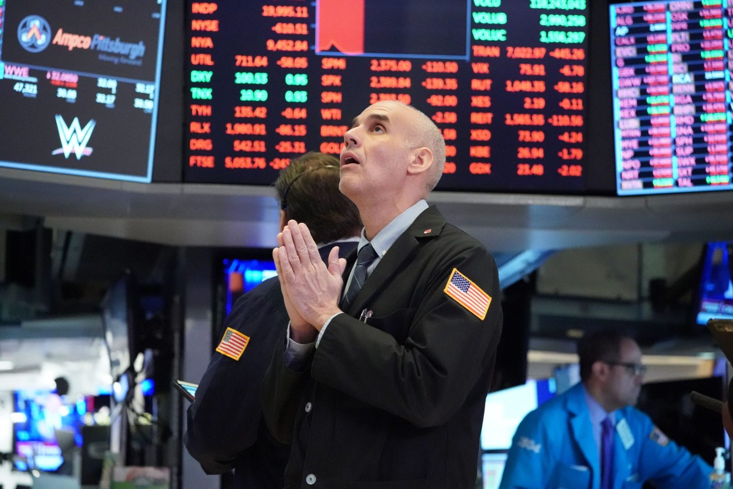 A trader on the New York Stock Exchange with hands together.
